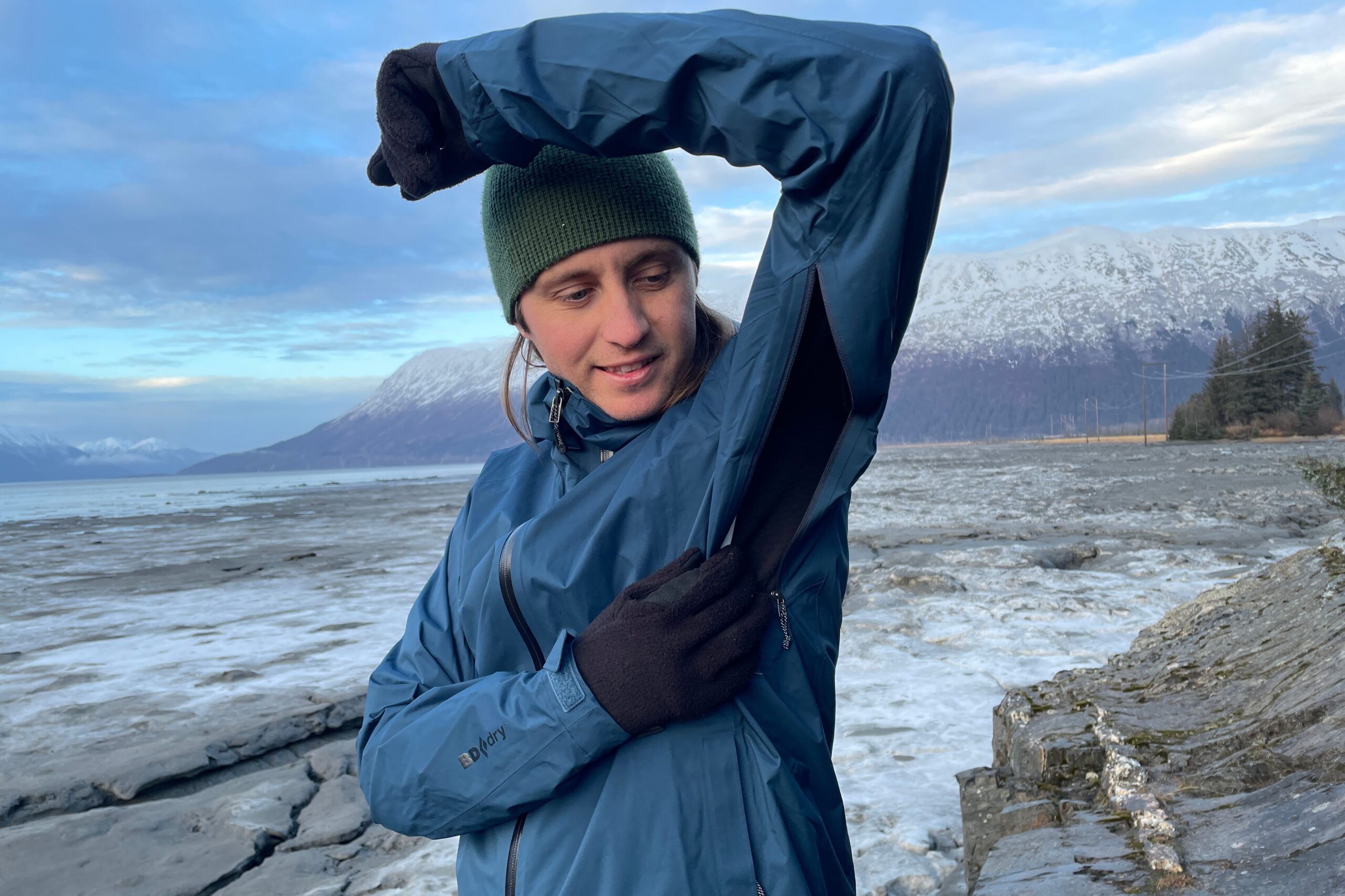 A man unzips the vents of his blue rain jacket.