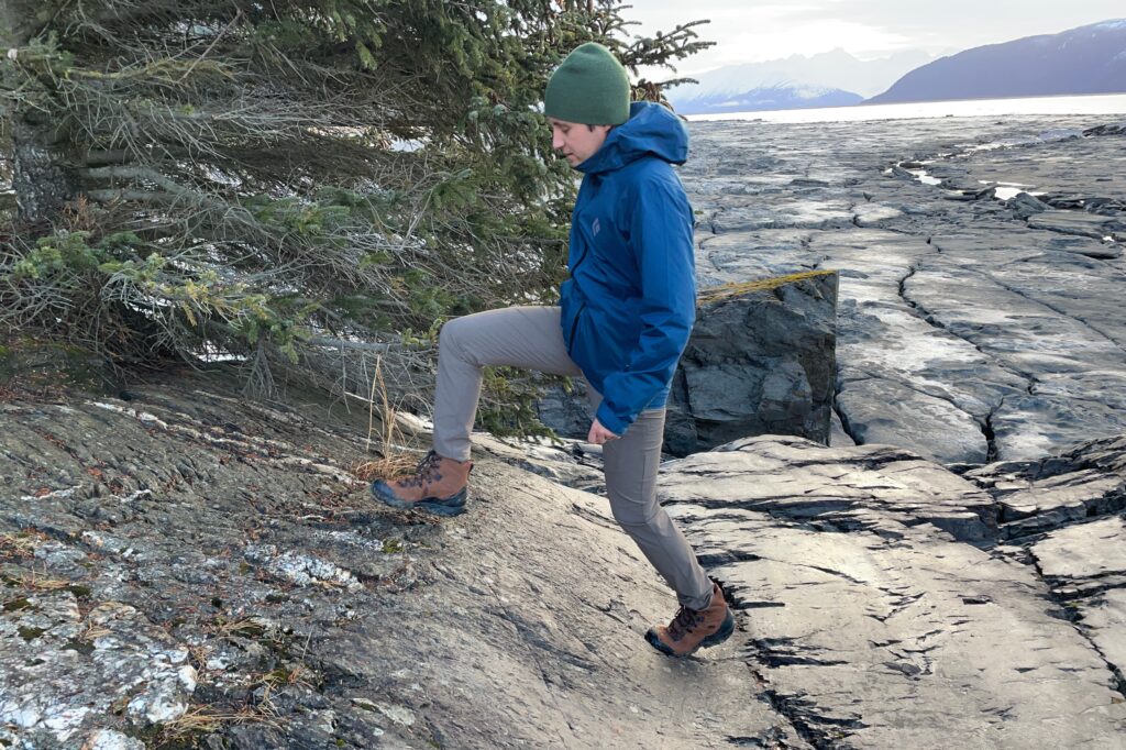 A man hikes along a rocky coastline.