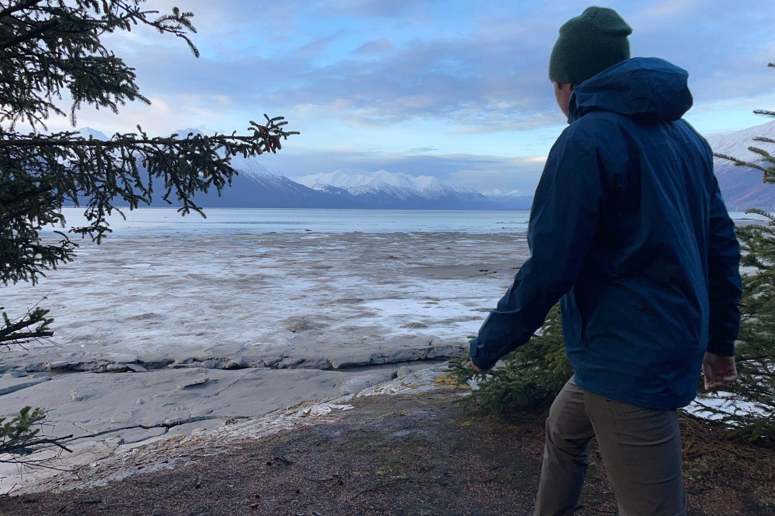 A man walks with an ocean and mountain view.