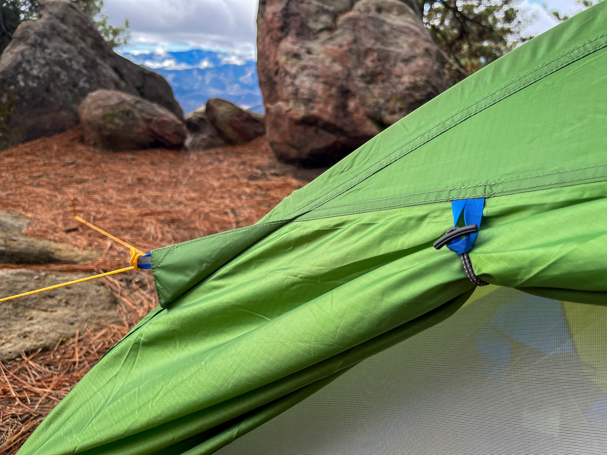 Closeup view of the door ties and extra guy line anchor points on the Marmot Tungsten 2. Rocks, trees, and mountains in the background.