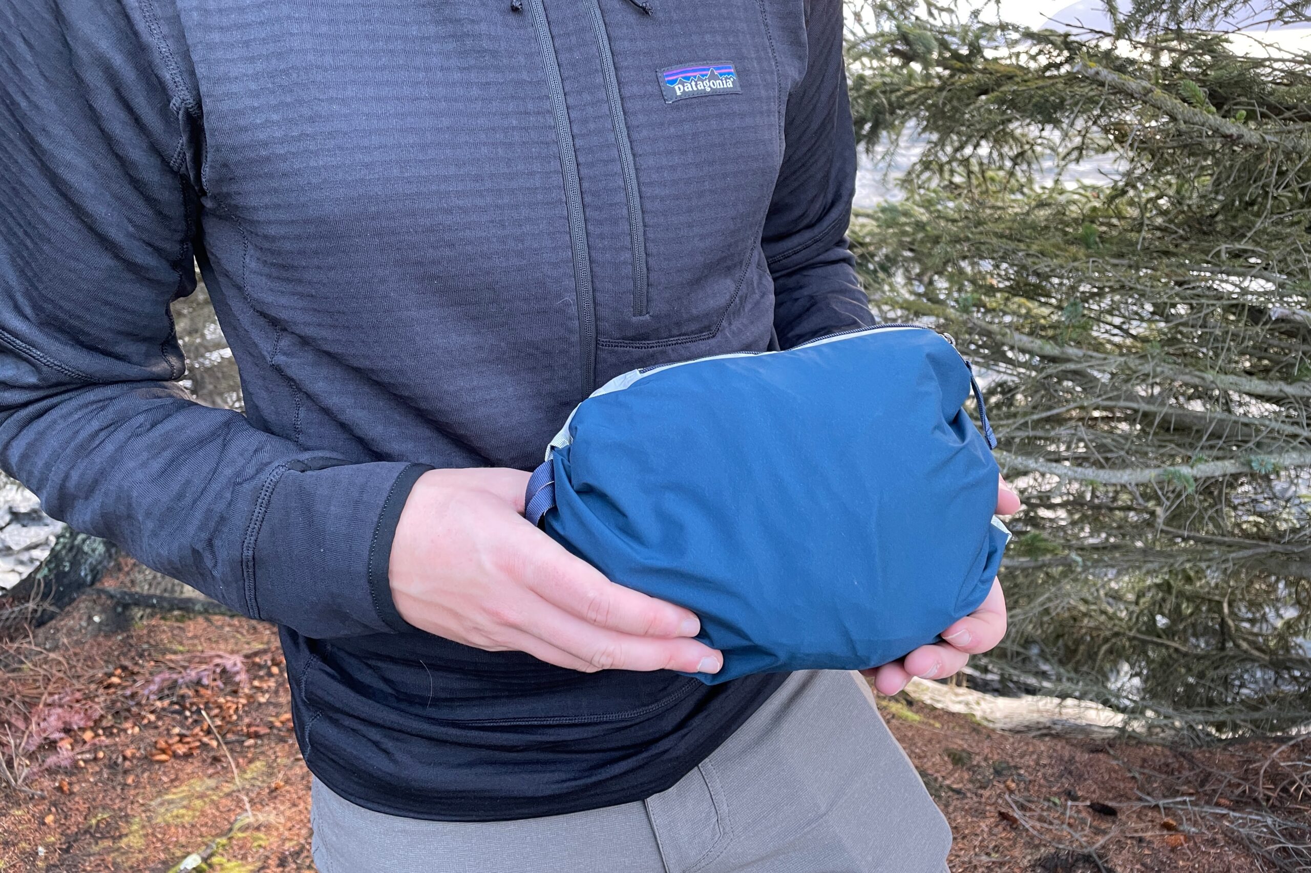 A man holds a jacket that is packed into a bundle.