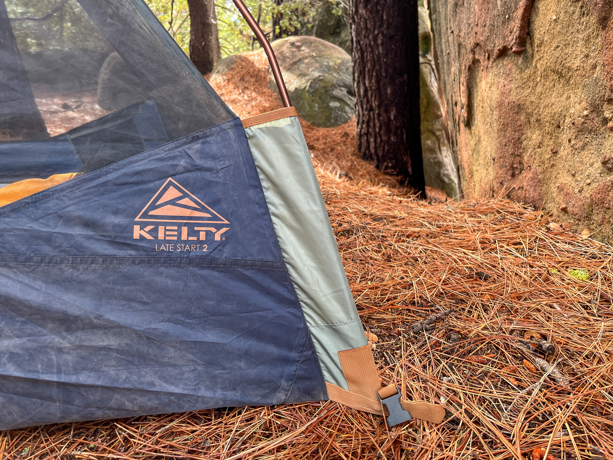 Closeup of the quick pole pockets and rainfly clip for the Kelty Late Start 2. rocks and pine trees in the background