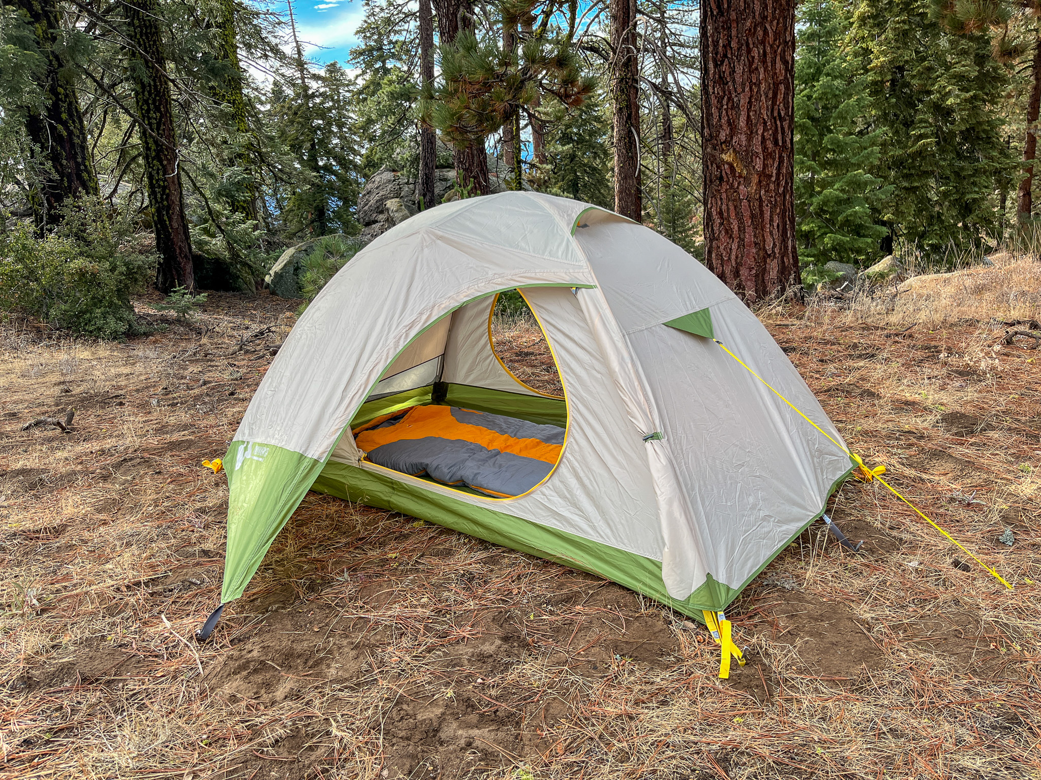 The Mountainsmith Morrison EVO 2 tent set up in a forest, showcasing its interior and vestibule storage.