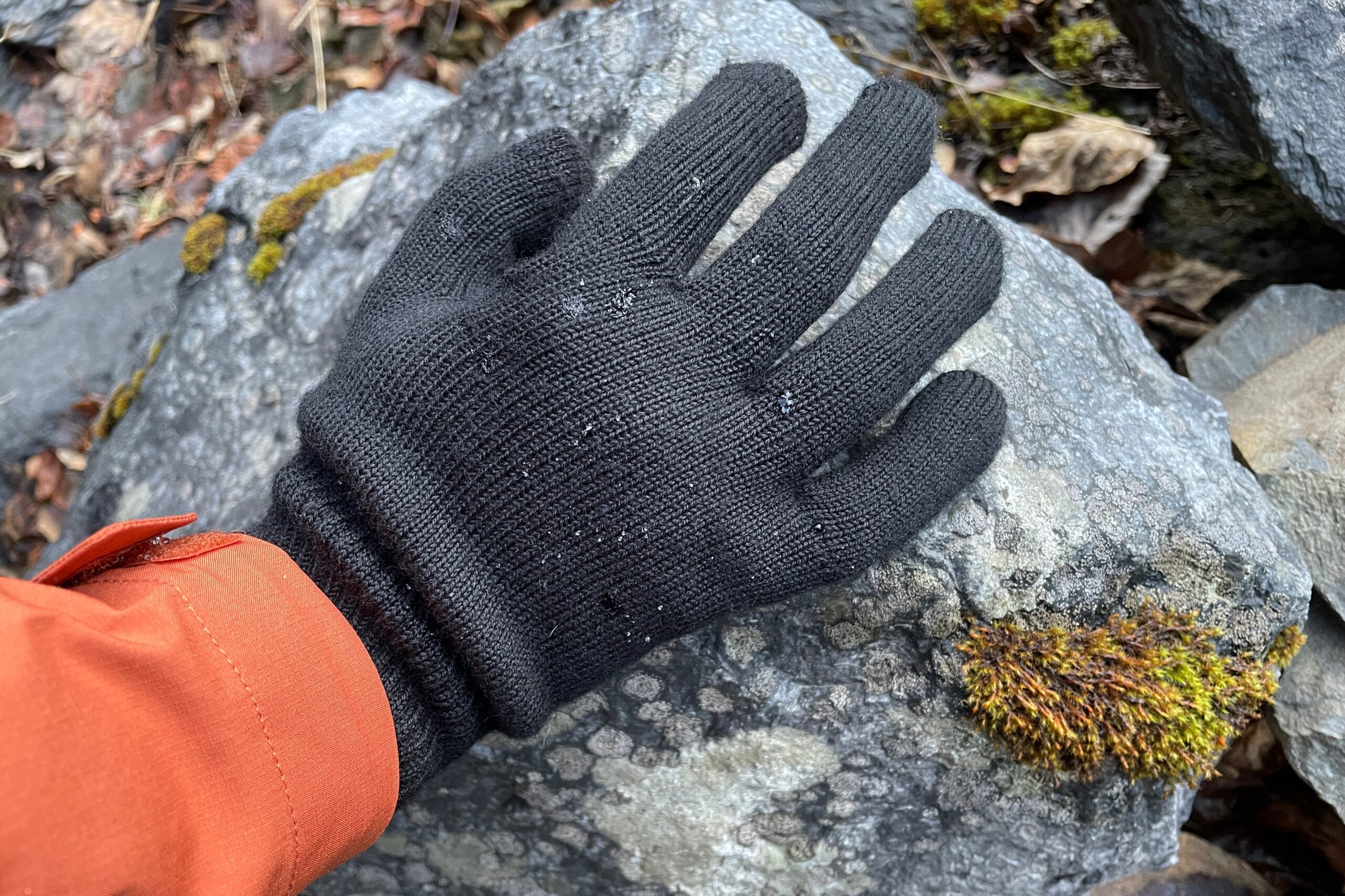 A closeup of a black glove with beads of water on it.