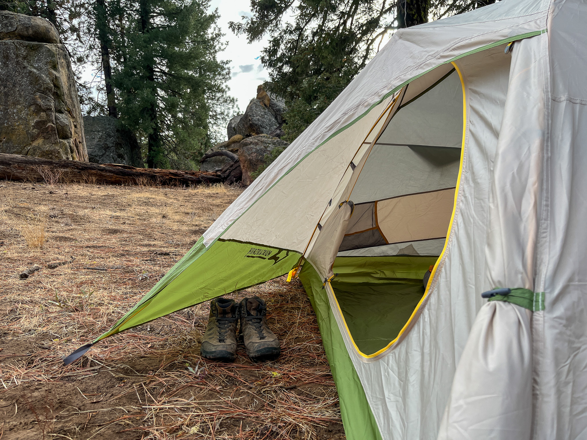 The Mountainsmith Morrison EVO 2 viewed from the side showing the interior vestibule space. The forest with a large rock formation in the background.