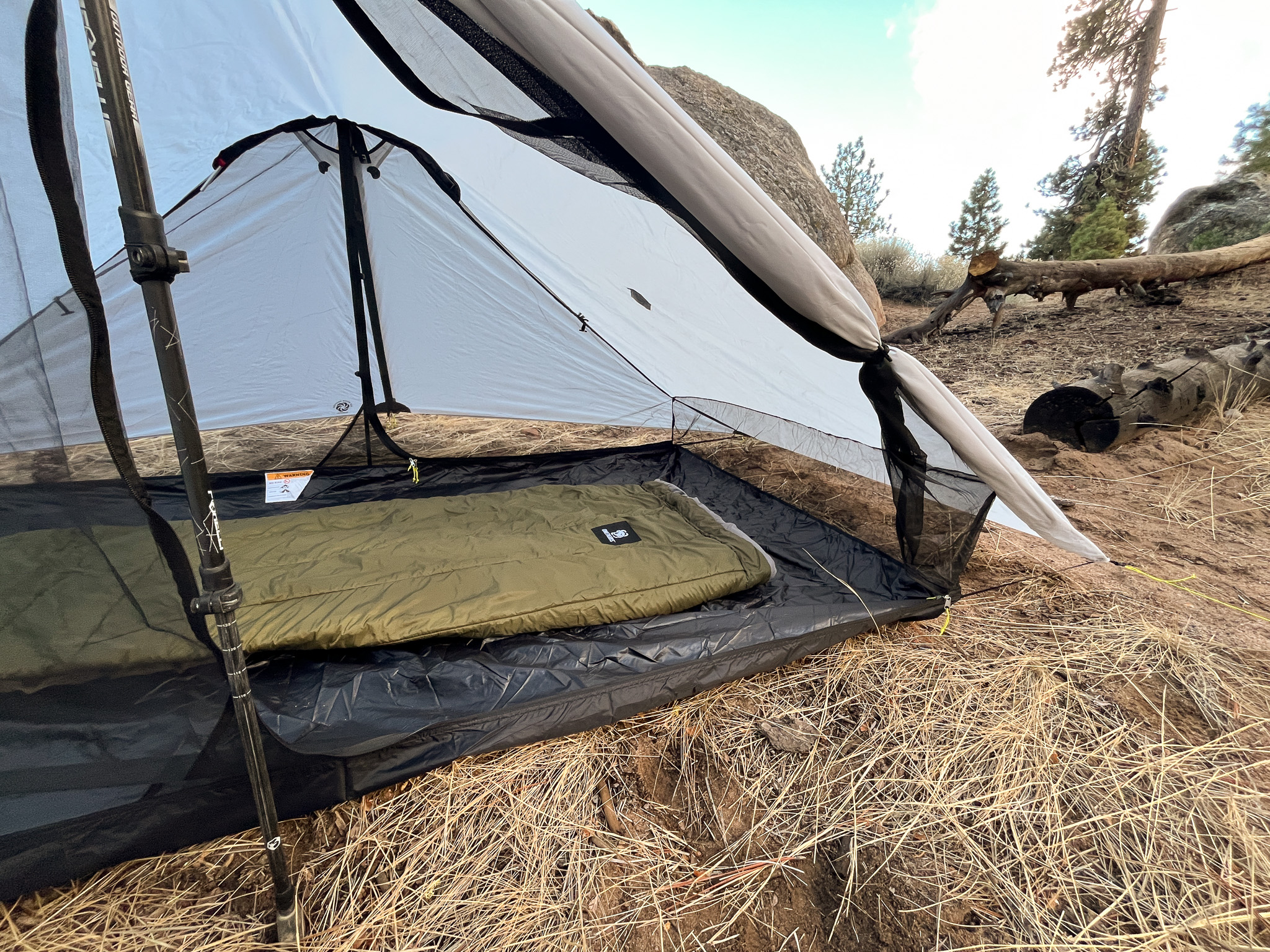 Closeup shot of the rolled back door and interior of the Six Moon Designs Lunar Duo Outfitter. It's showing the integrated canopy walls along with the remaining mesh areas and a sleeping bag.