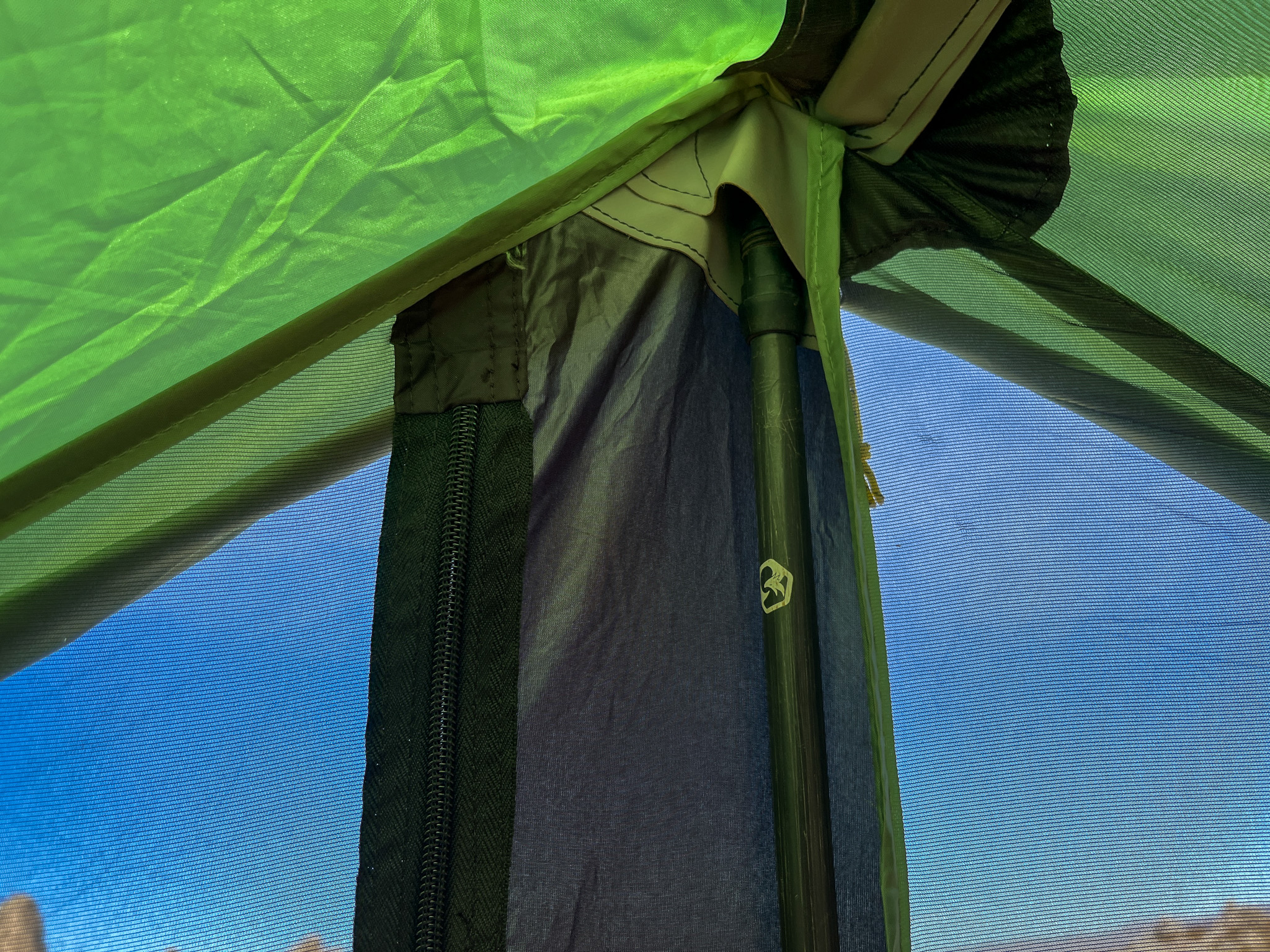 Closeup view of the reinforced interior pole tip pockets at the top of the doorway on the Six Moon Designs Skyscape Scout tent. Blue sky is visible outside the mesh.