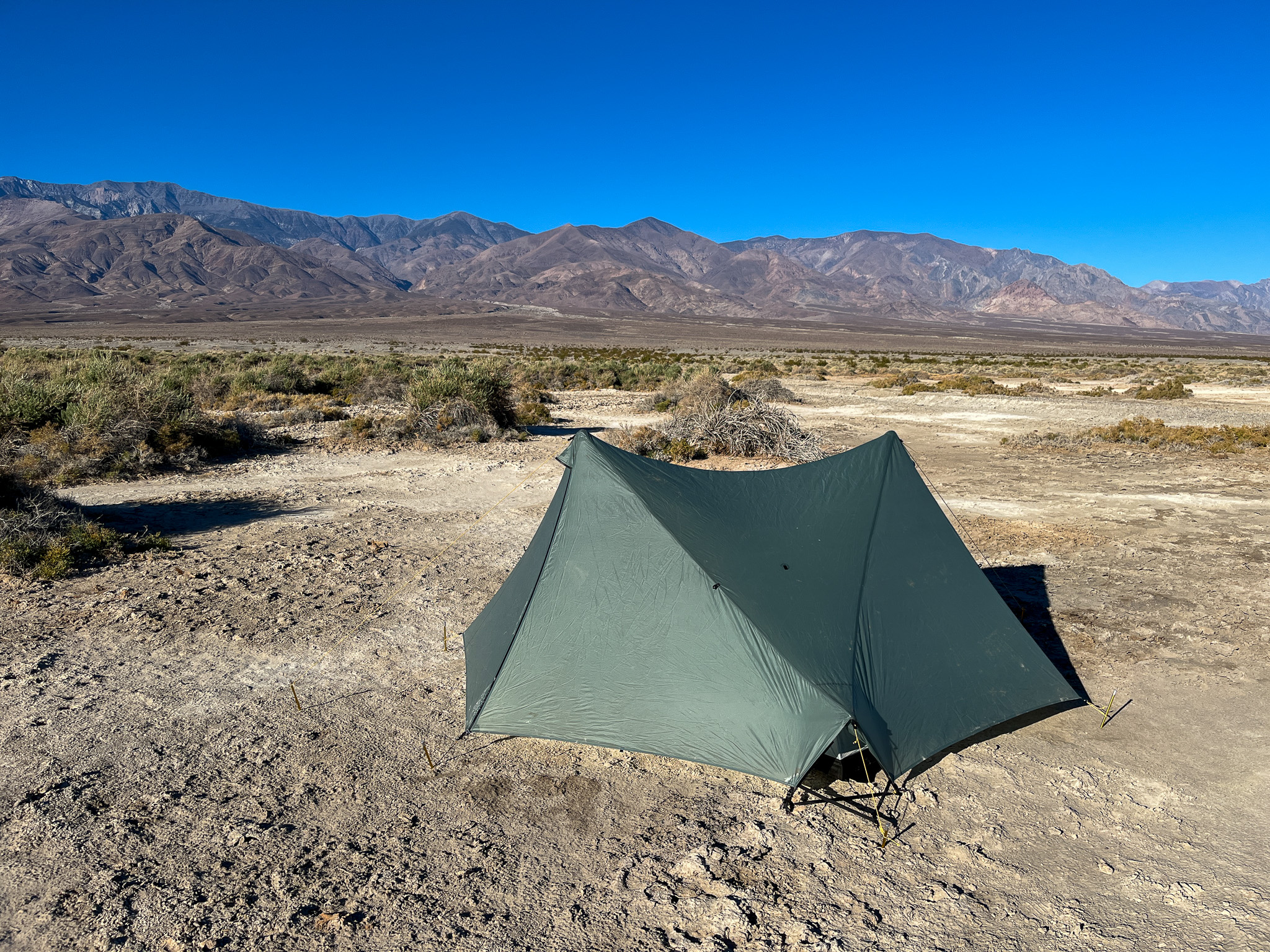 View of the Tarptent Stratospire 2 with a fully zipped up rainfly, and the lower pitch-lock vents open. The desert and distant mountains in the background.