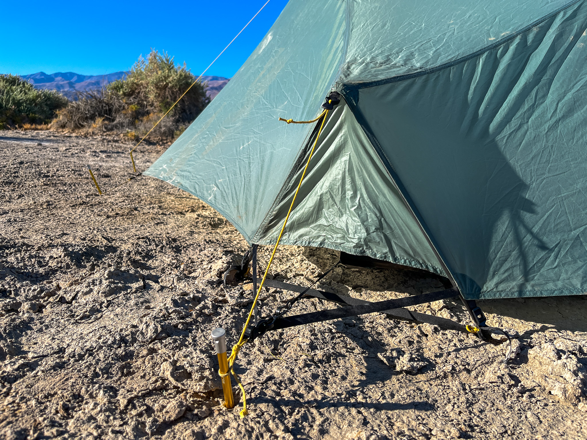 Closeup shot of the lower pitch-lock vents, tension adjuster, and stake. Deset bushes and mountains in the background.