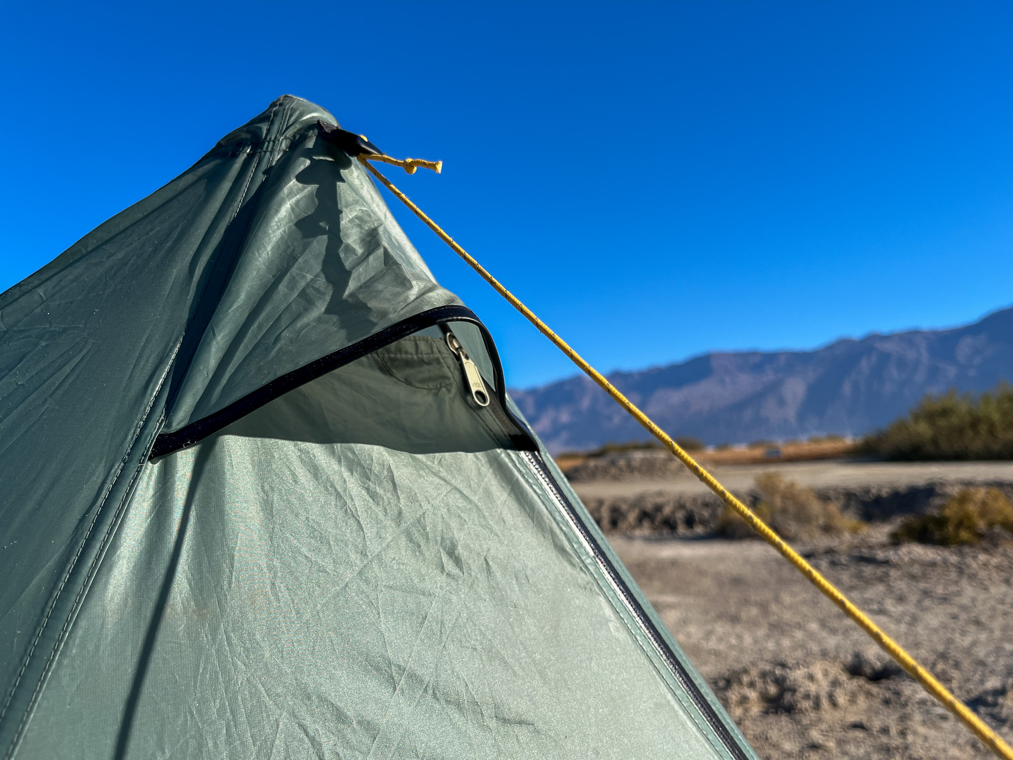 Closeup of the flexible hooded vent and adjustable apex guy line for structural stability. Desert and mountains visible in the background.