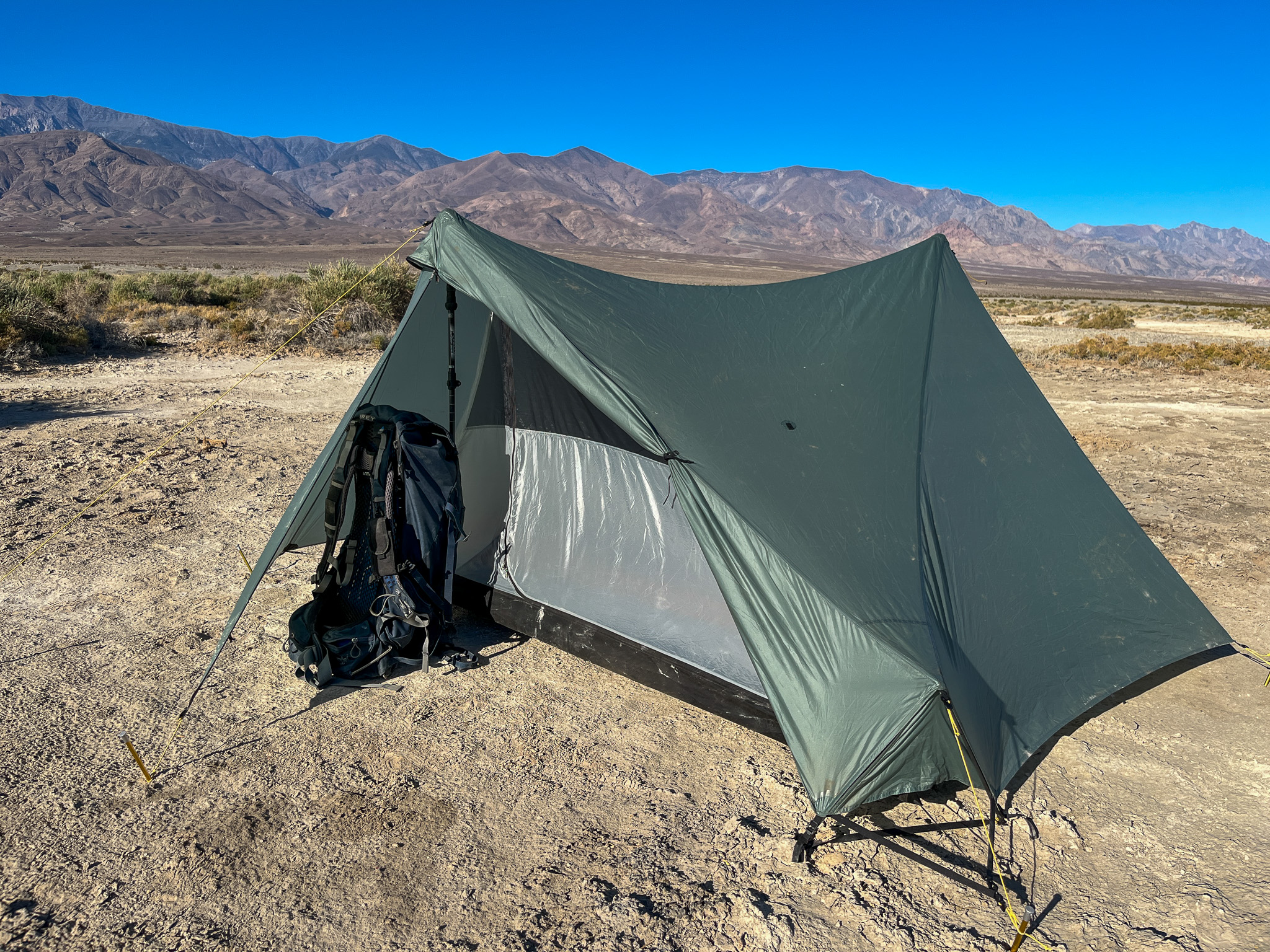 View of the Tarptent Stratospire 2 with one of the vestibules open. It shows a backpacking pack underneath the other half leaning against a trekking pole.