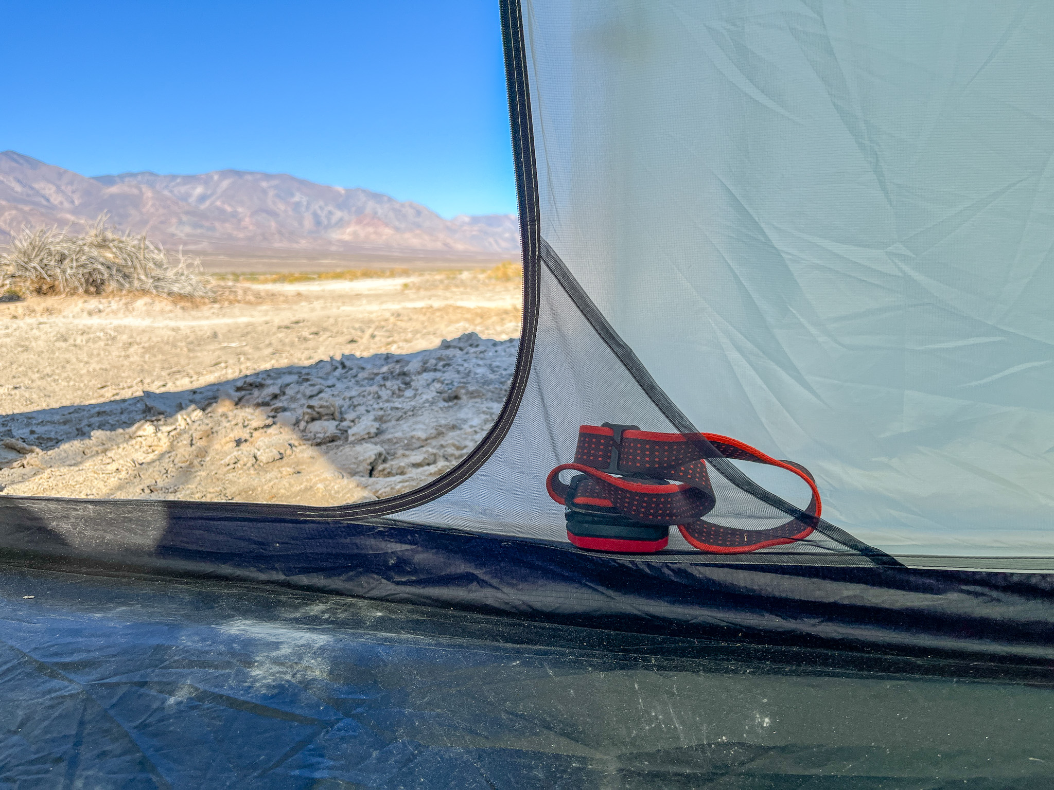 Closeup view of one of two interior pockets with a red headlamp inside. The surrounding desert and mountains are visible outside through the mesh.