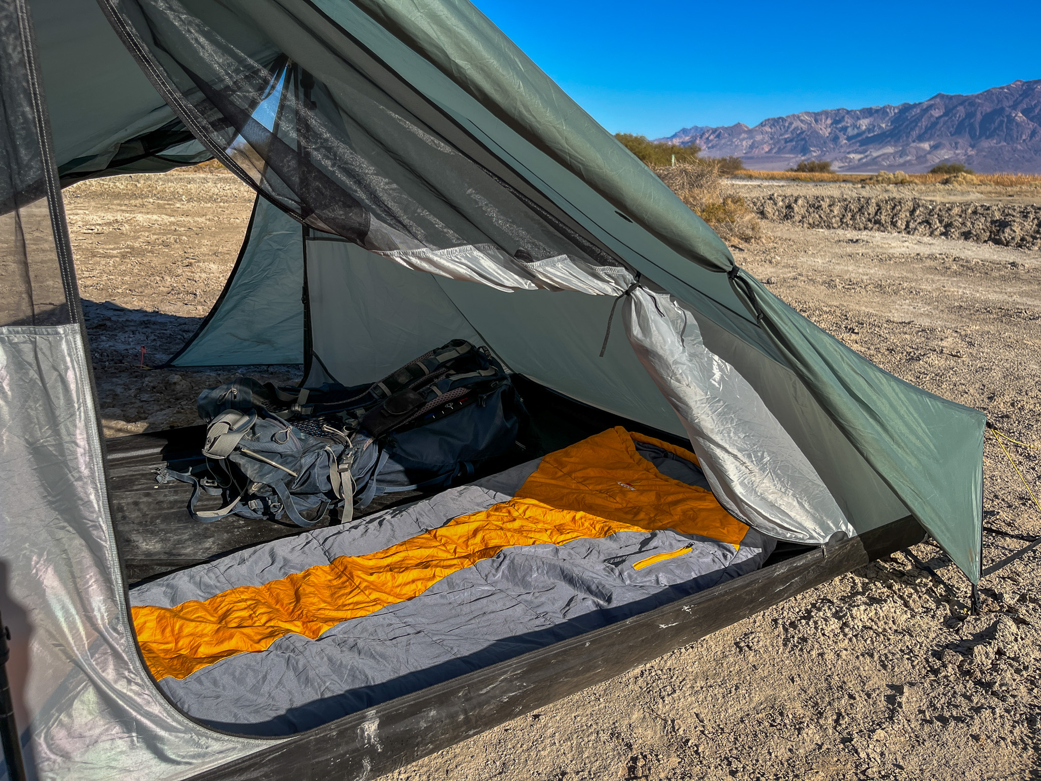 Interior view of the Tarptent Stratospire 2. Shows a sleeping bag and backpacking pack inside with the opposite door and vestibule also open. Desert and mountains visible in the background.