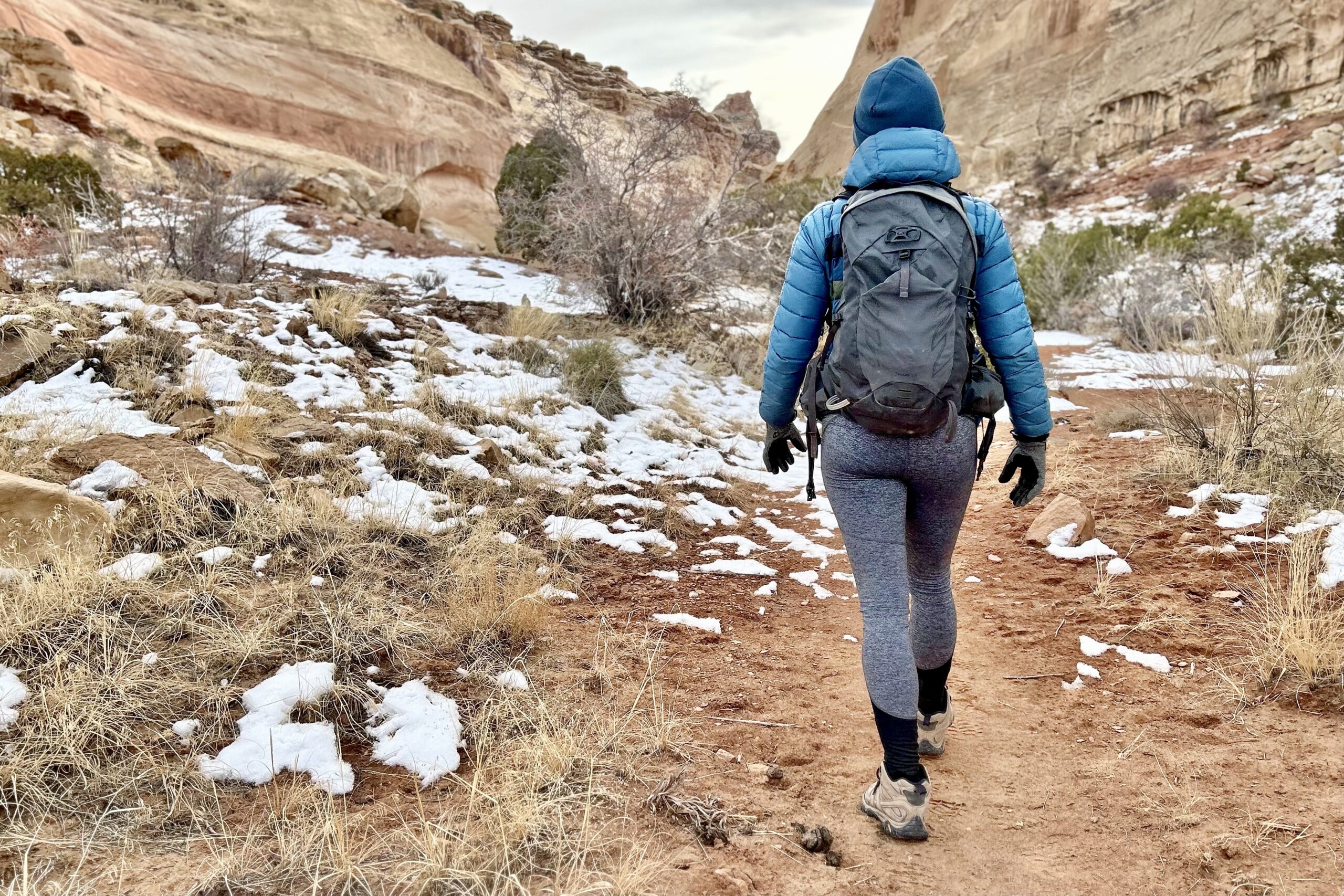 Picture of a woman hiking away from the camera and into a canyon.