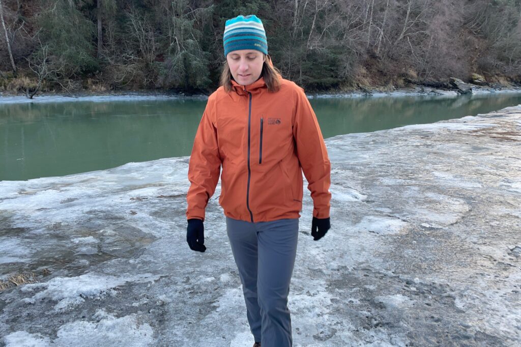 A man walks along an icy riverbank.