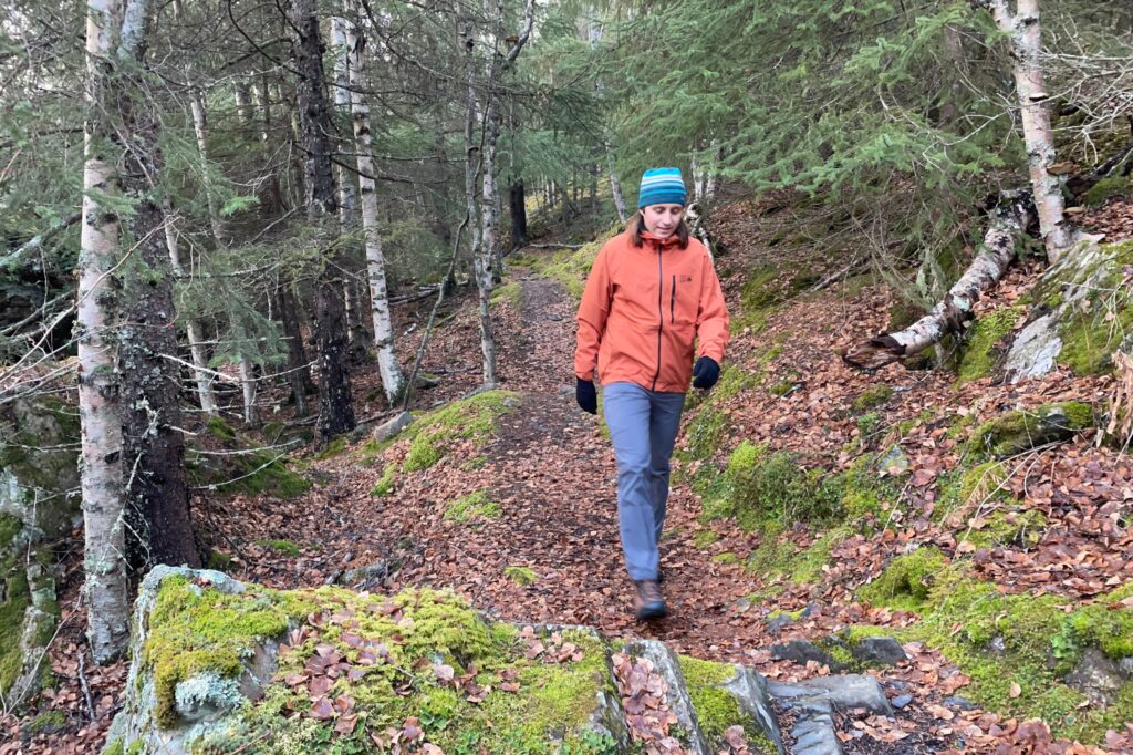 A man walks down a mossy trail.