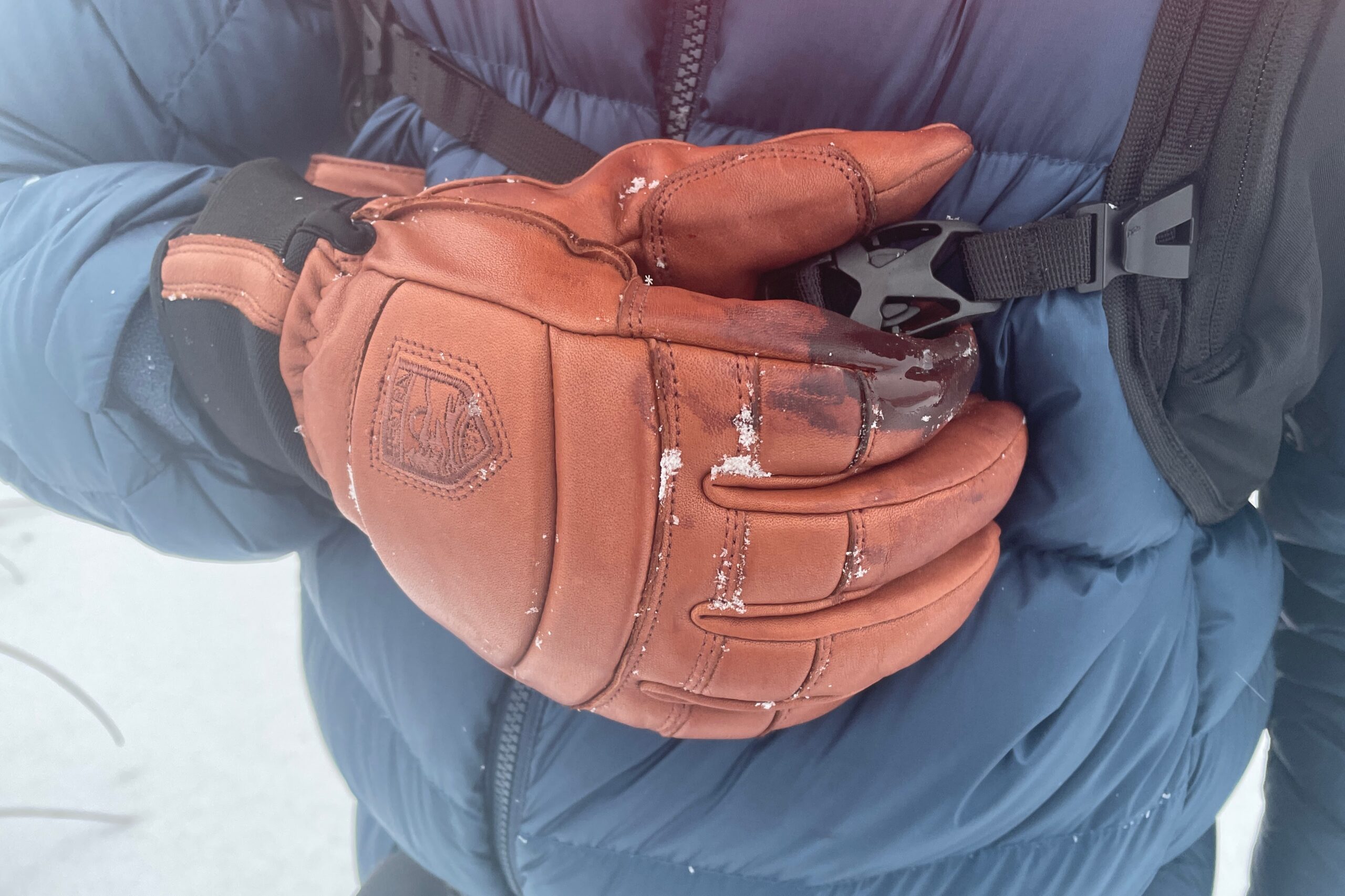 A closeup of gloves unbuckling a backpack.