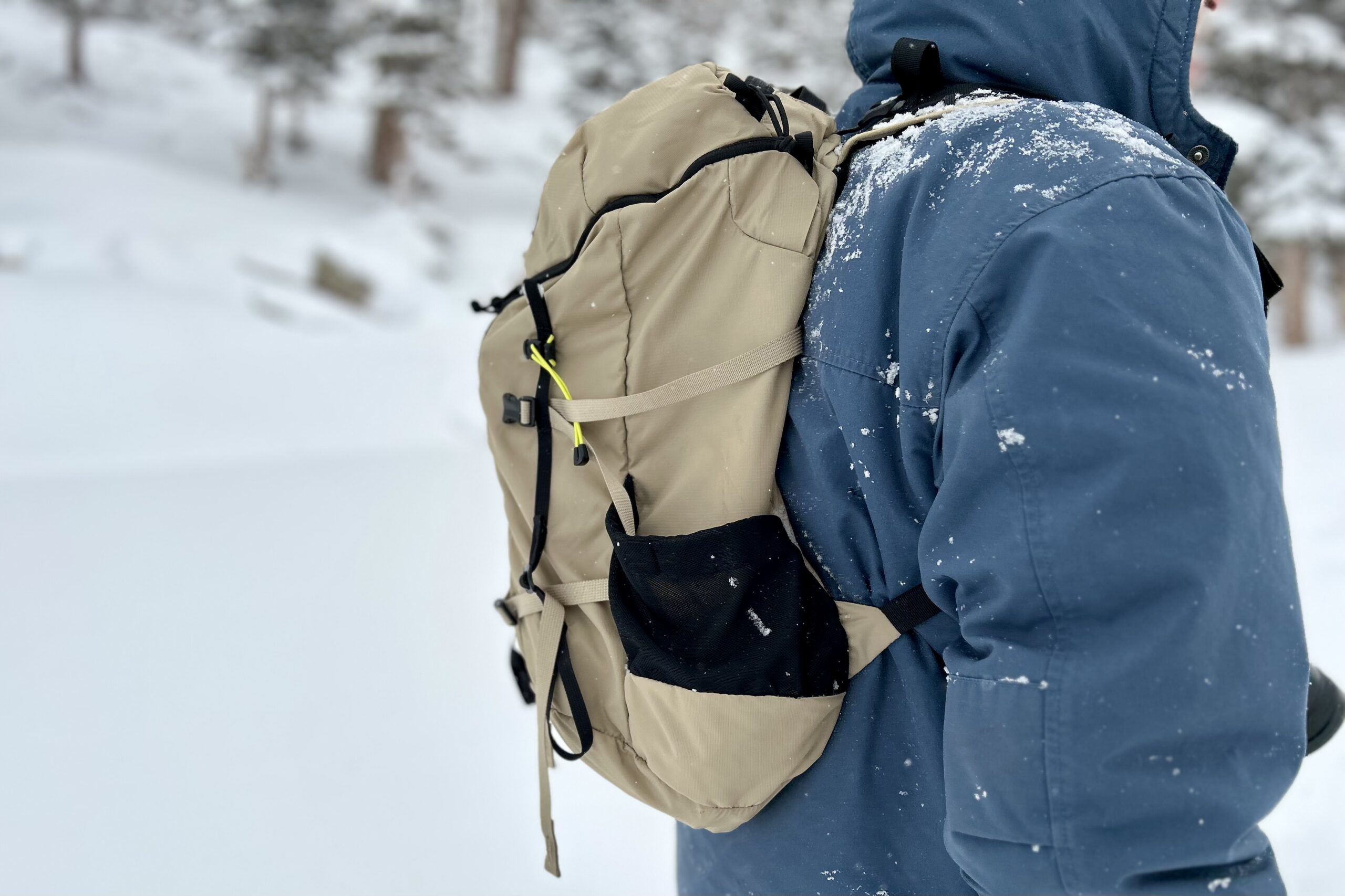 Close up of a daypack as a man hikes through a wintry scene.