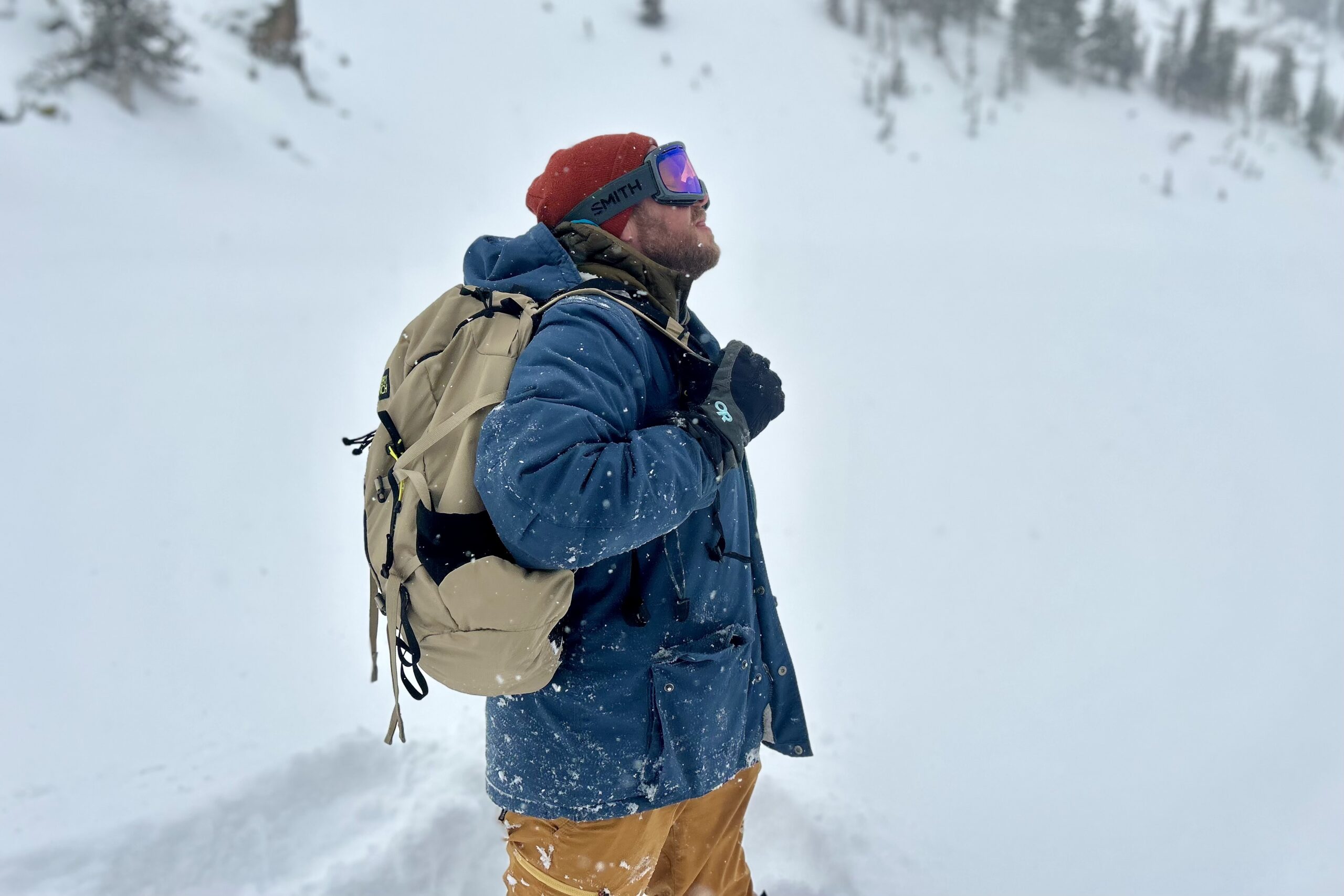 A man hikes with a daypack in a wintry mountain landscape.