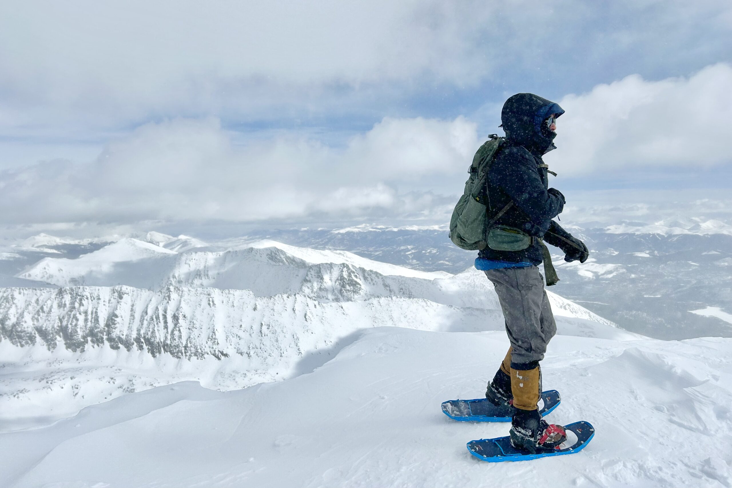 a hiker wearing snowshoes on an overlook in a snowy landscape