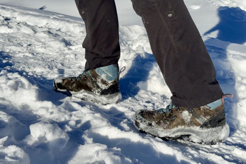 A close up of a person walking in the snow wearing the Keen boots.