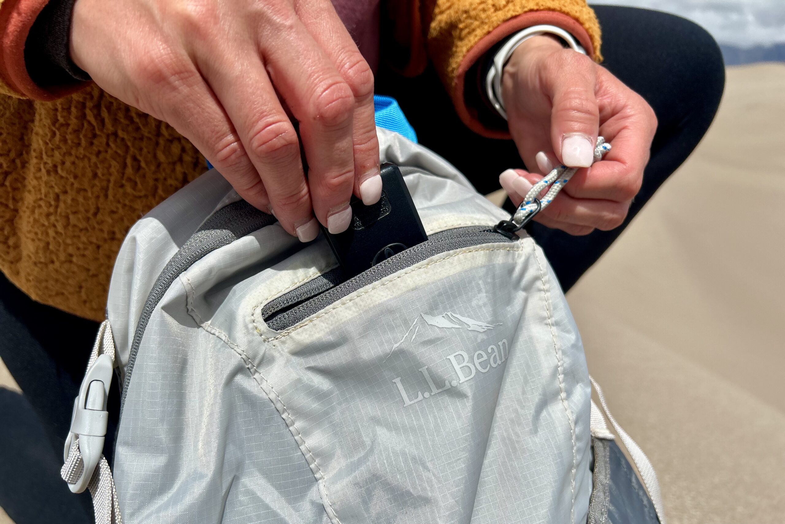 Close up of a person putting keys into a zippered backpack pocket.