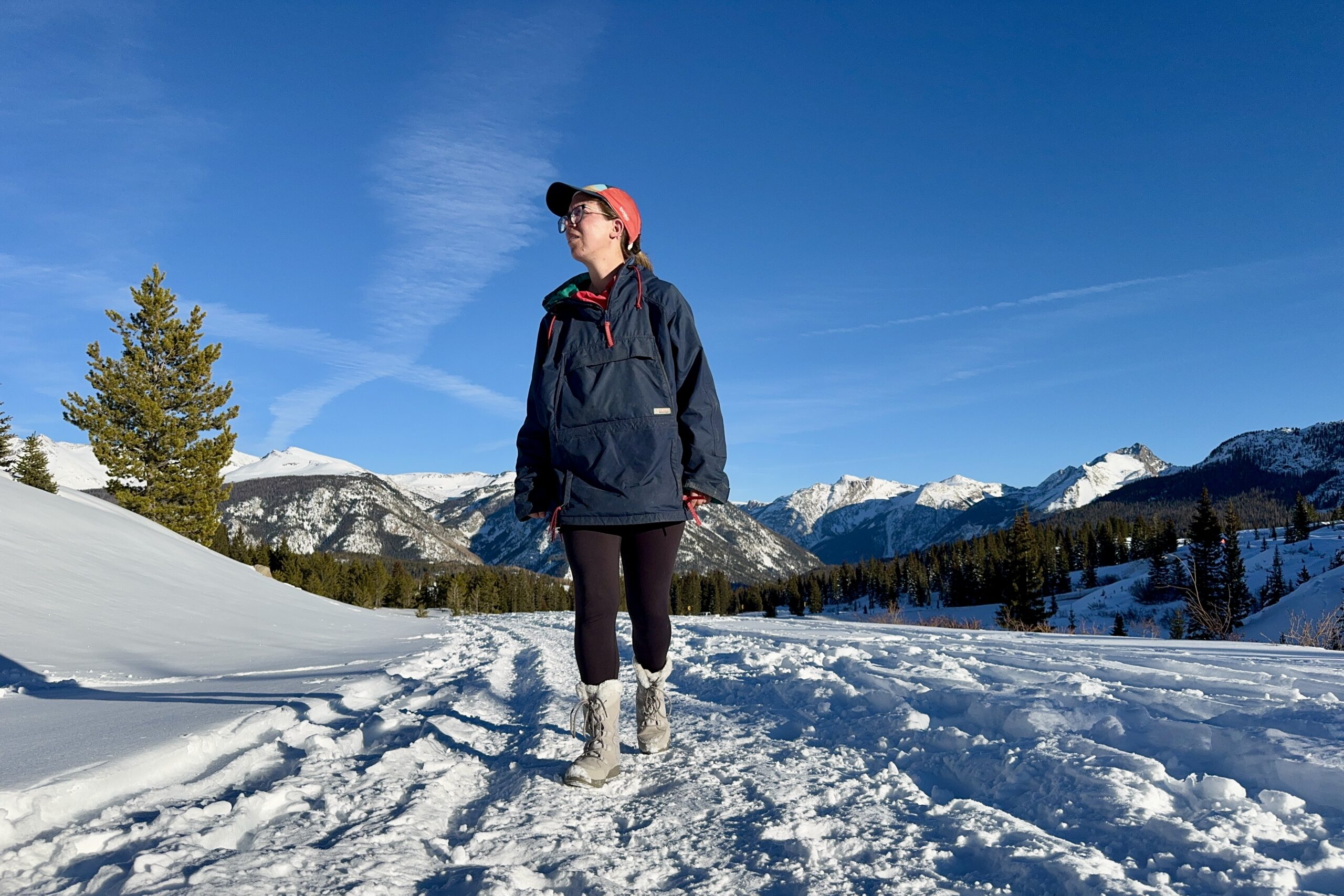 A person wearing the Ice Maiden boots is walking in the snow with some mountains in the background.