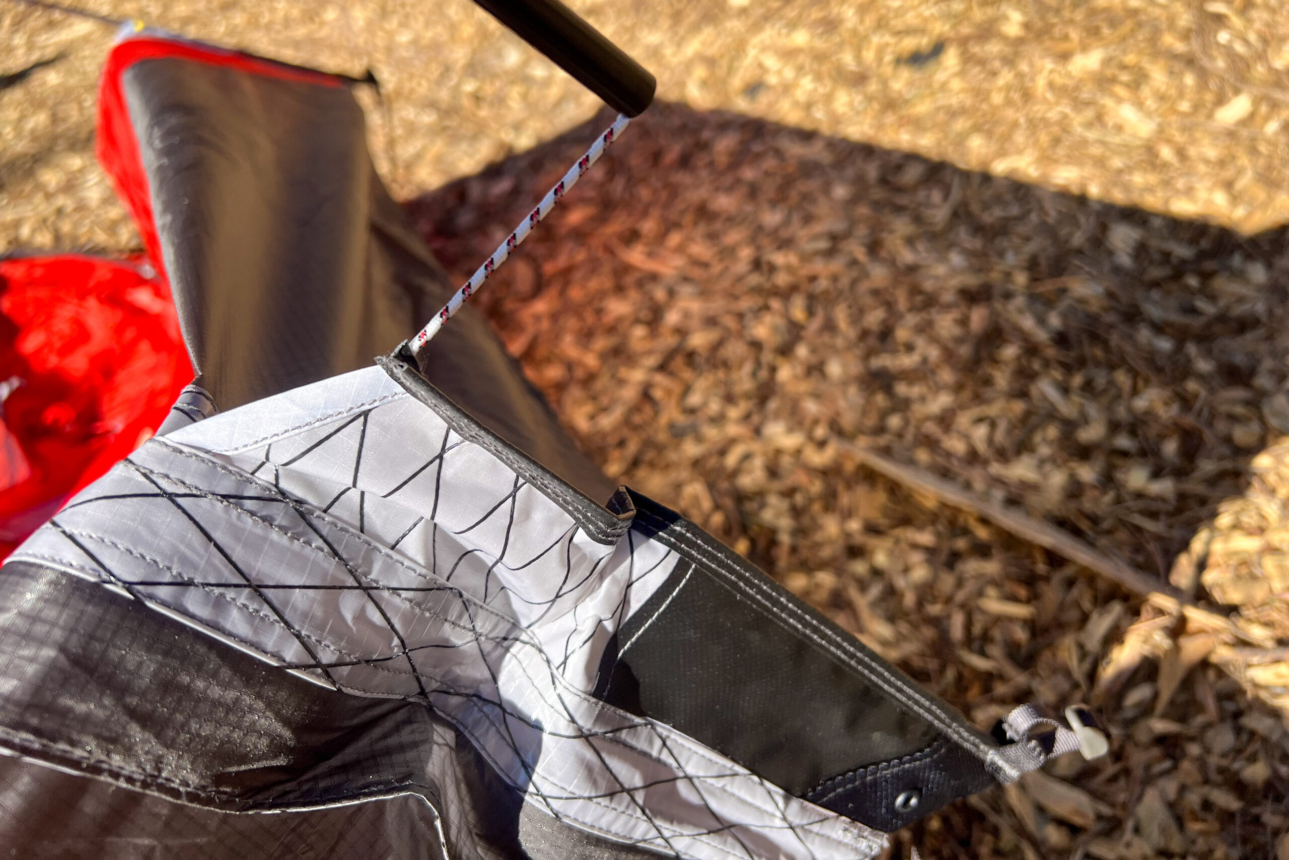 Close-up of a guyline attachment on the KUIU Storm Star 2 tent, highlighting the durable stitching and reinforced connection points with reflective guylines.