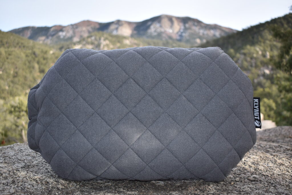 Close up of the Klymit LUXE pillow fully inflated with mountains blurred in the background