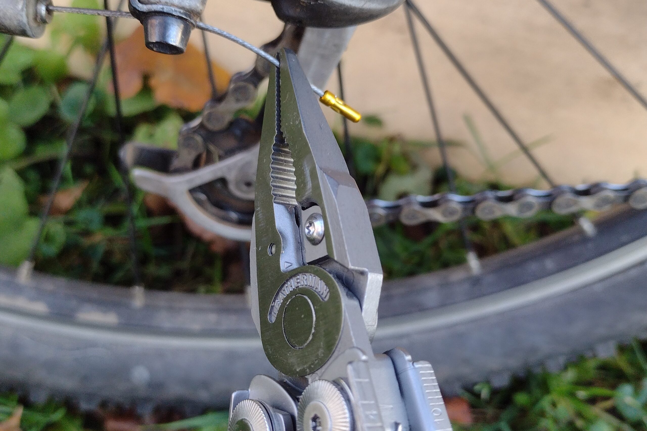 The Leatherman Surge with its needle-nose pliers bending a bicycle's derailleur cable.