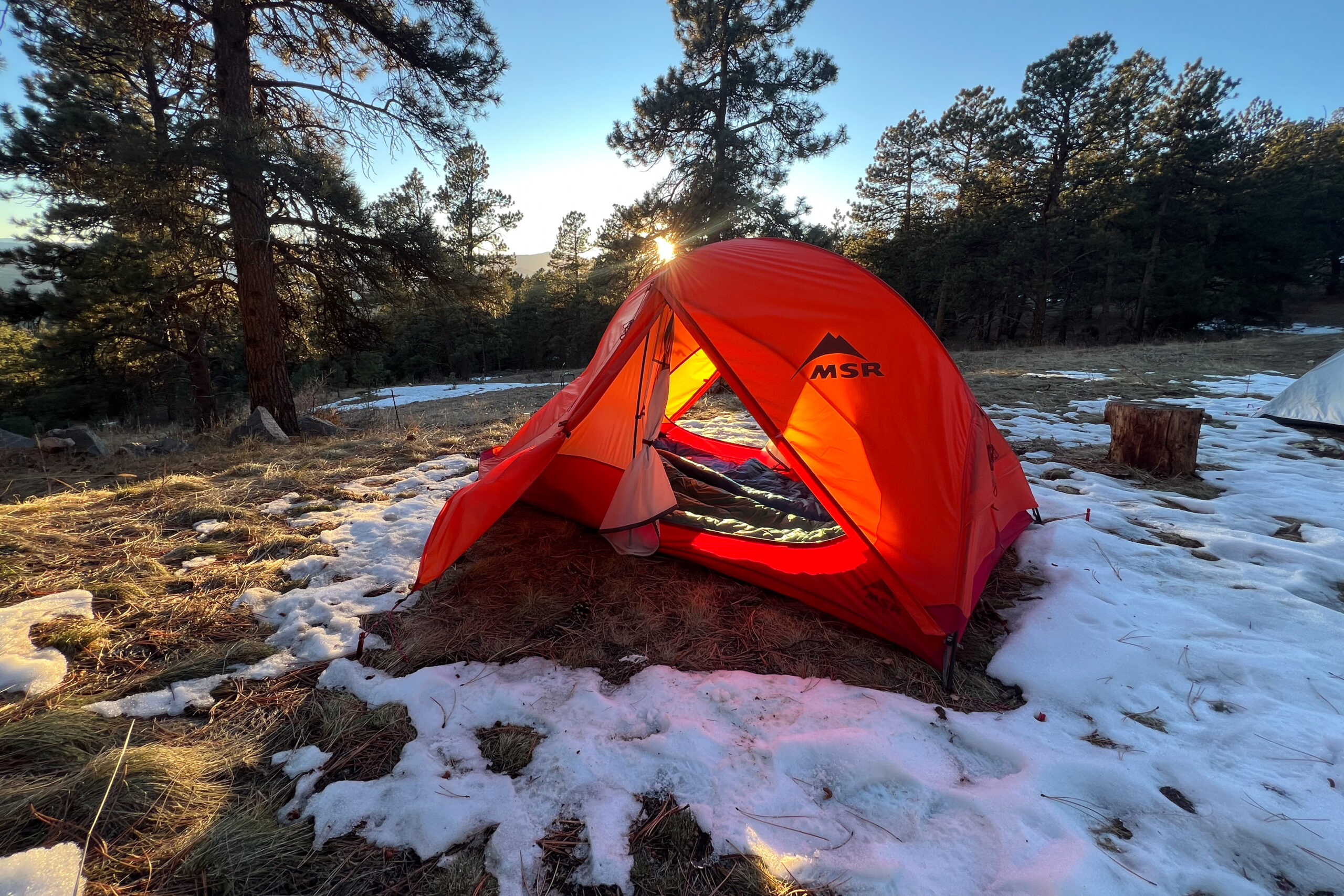 Rear view of the MSR Access 2 tent covered in snow with trees in the background.