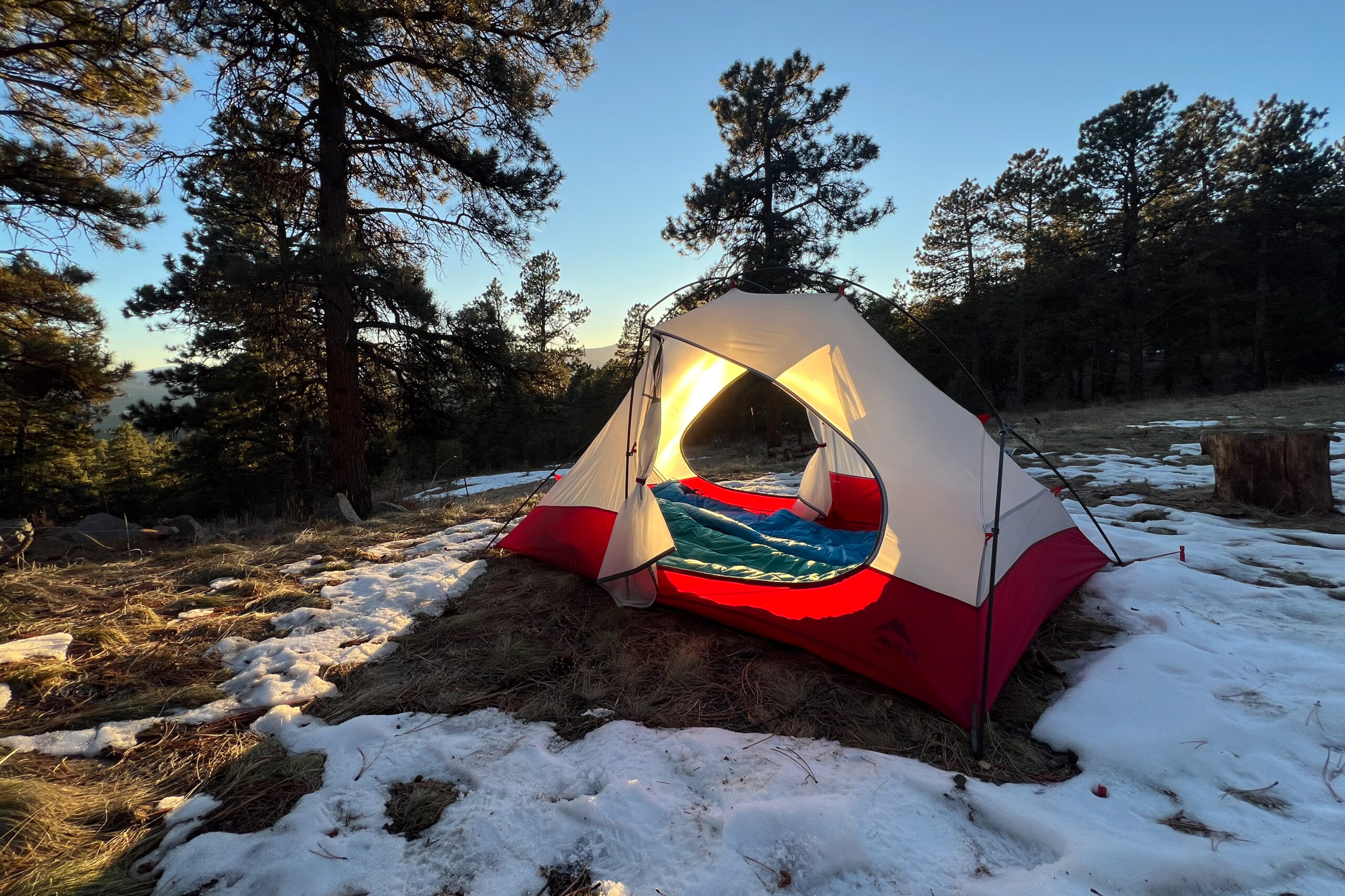 A front-facing view of the MSR Access 2 tent pitched in snow-dusted ground during sunset.