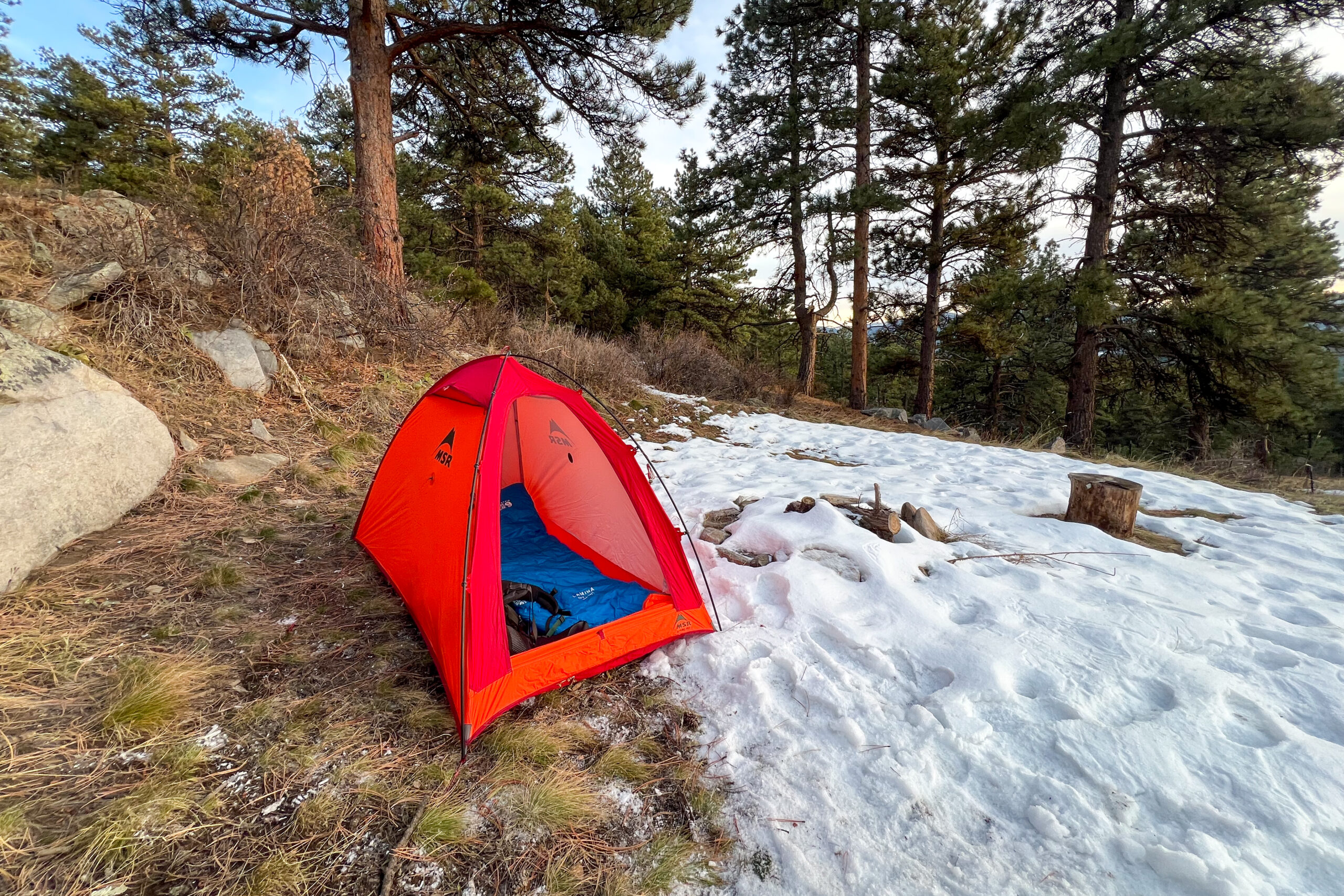 Interior view of the MSR Advance Pro 2 tent, with two sleeping bags arranged on the floor and sunlight filtering through the red fabric.