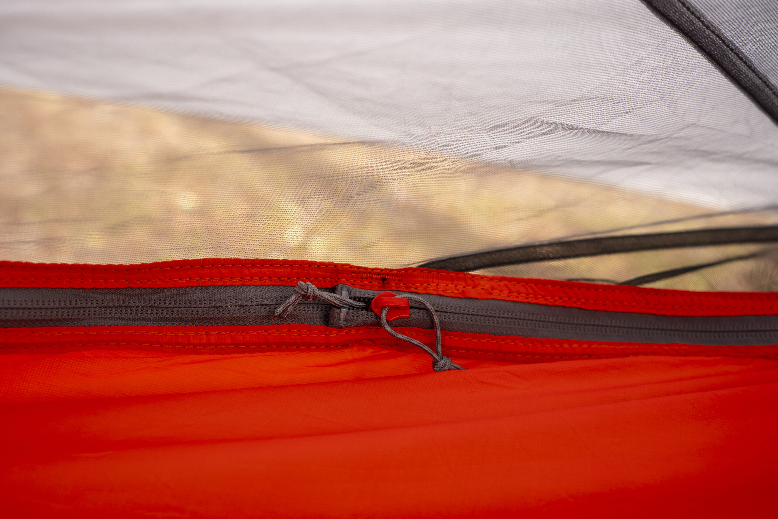 A zipper on the side of a hammock with bug netting