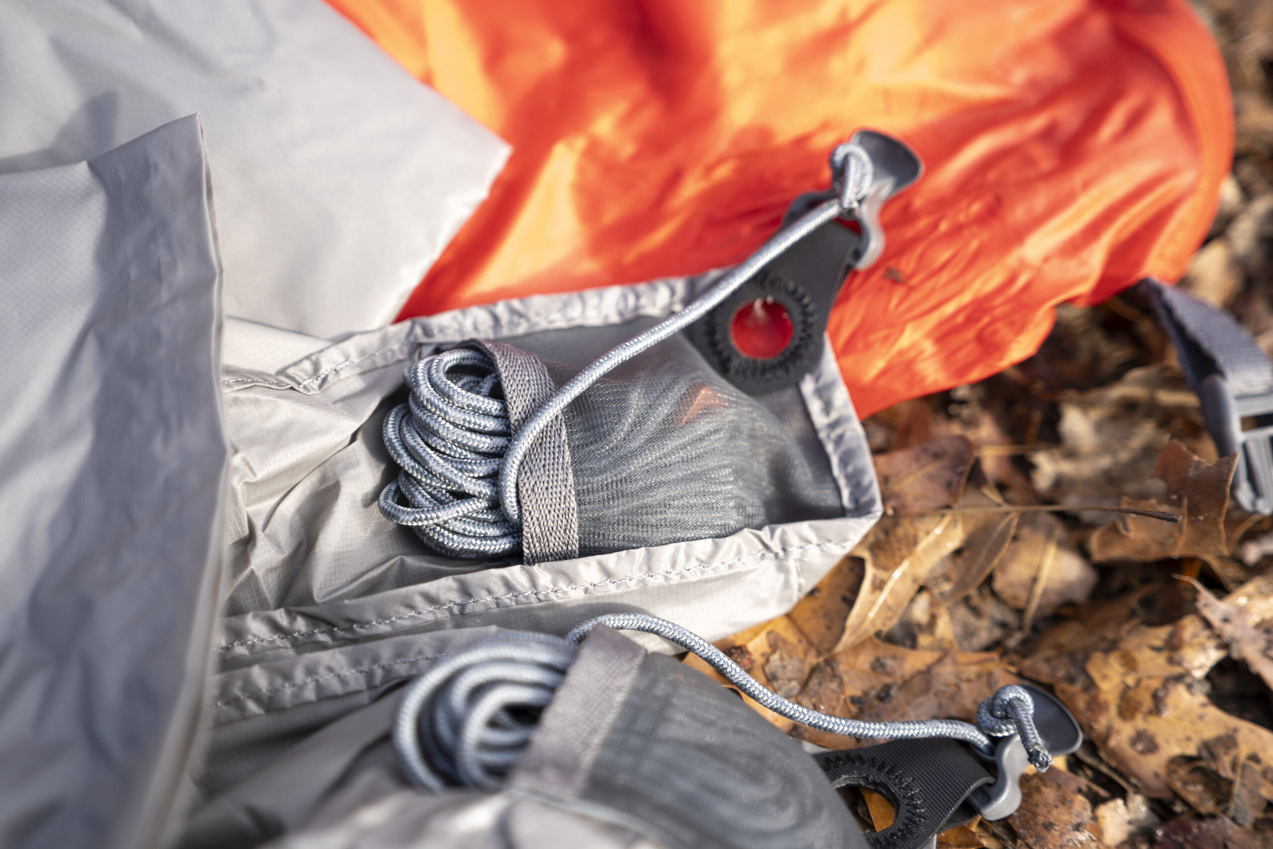 A length of cord is tucked into a mesh pocket on a corner of a tarp