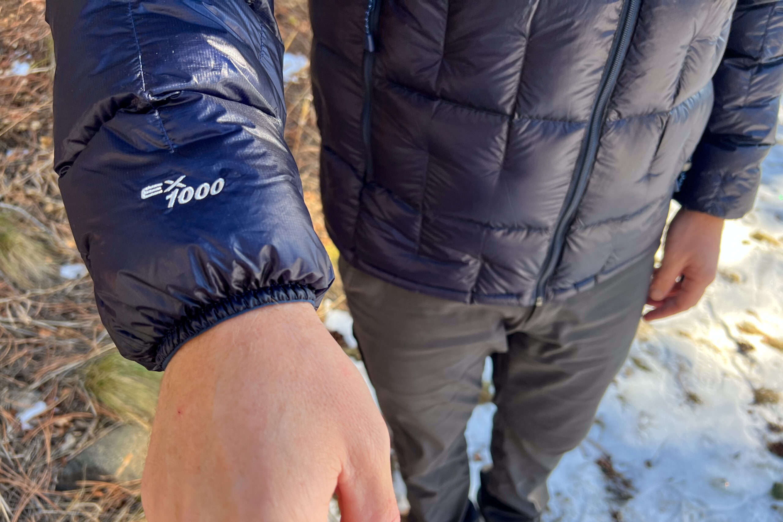 Close-up of the sleeve of the MontBell Plasma 1000 Alpine Down Parka, showing the "EX 1000" logo embroidered near the cuff.