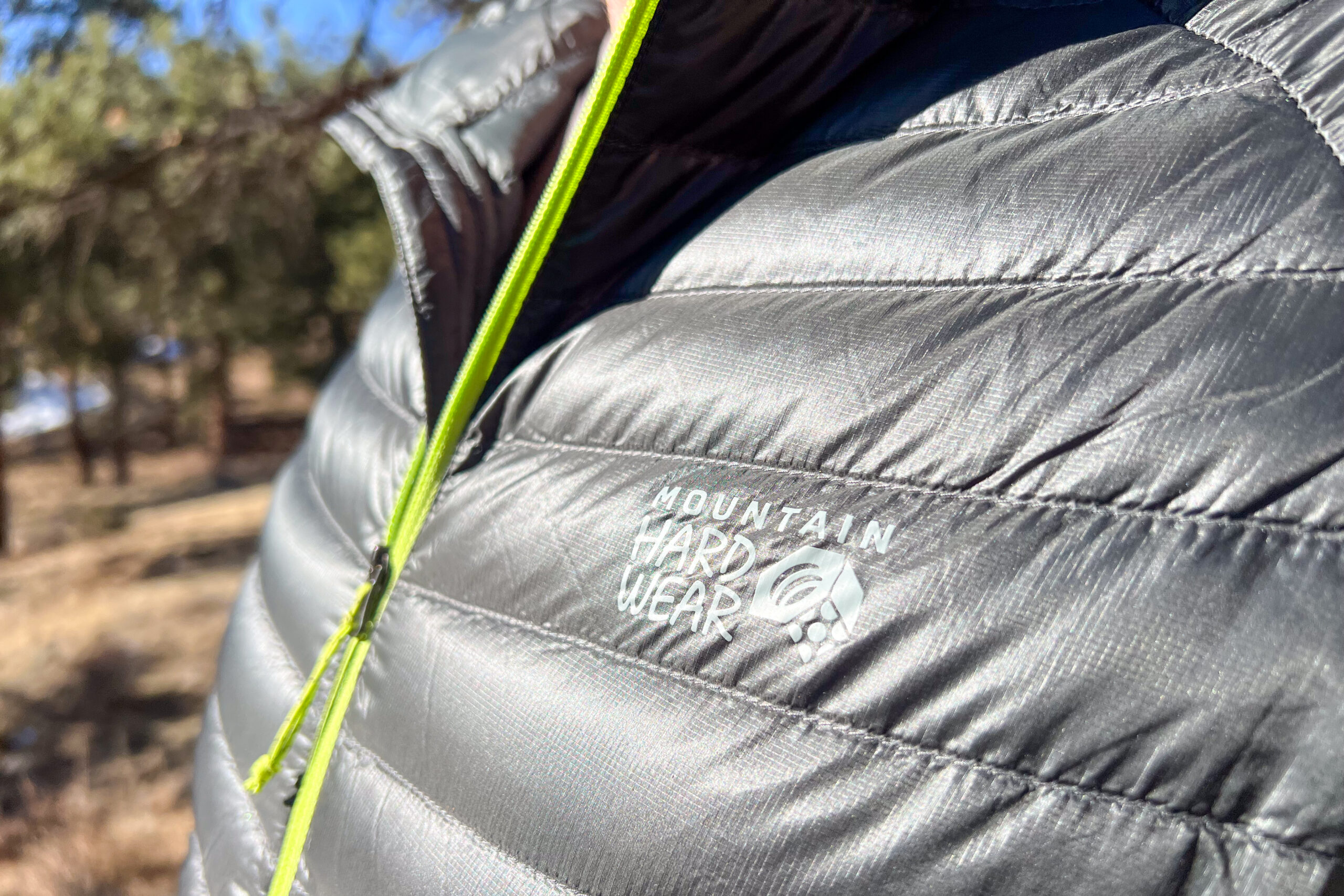 Close-up of the Mountain Hardwear logo on the shiny, gray fabric of the Ghost Whisperer/2 jacket.