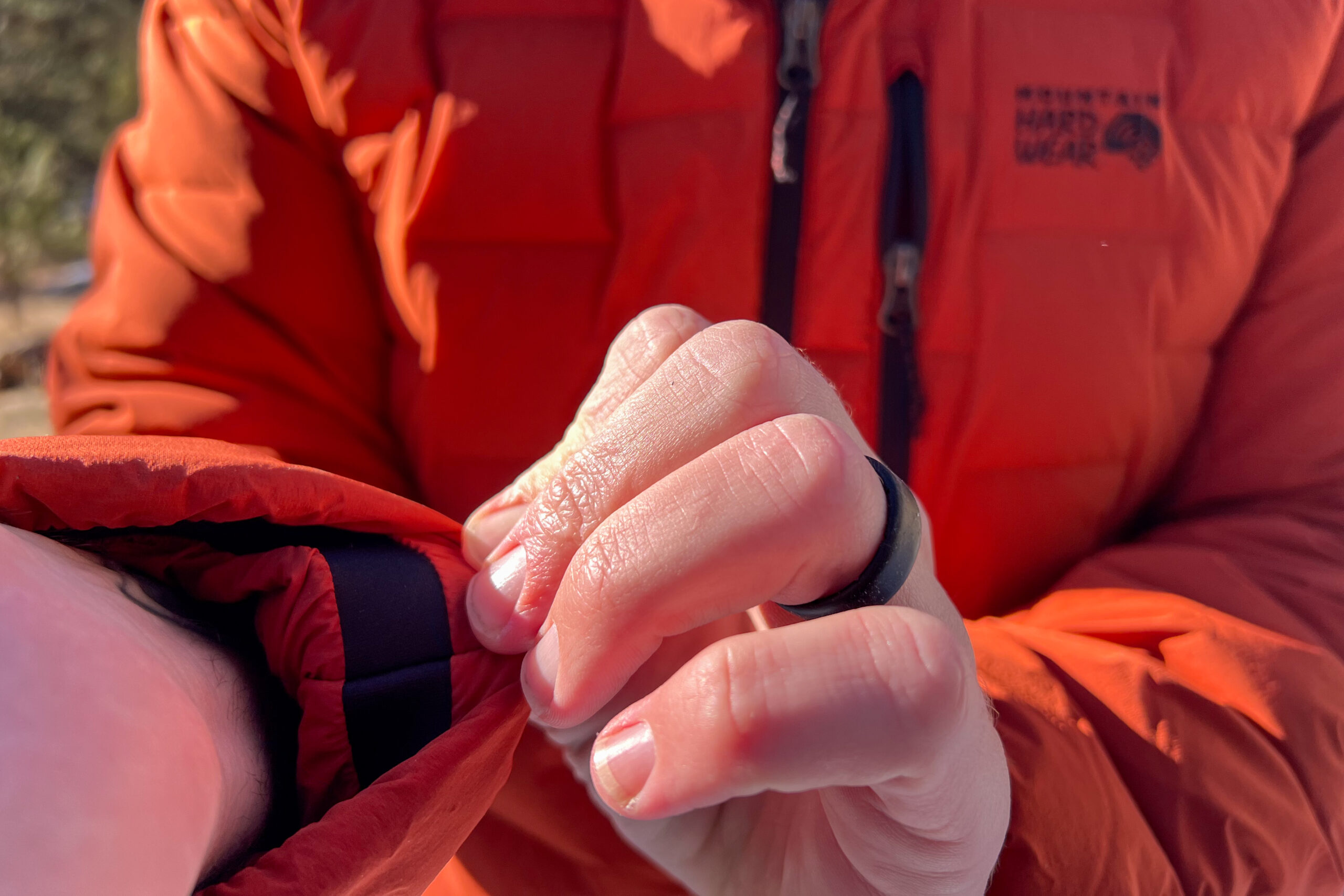 A close-up of a person adjusting the elastic cuff of the Mountain Hardwear StretchDown Hoody, highlighting the stretchy fabric and secure wrist fit.