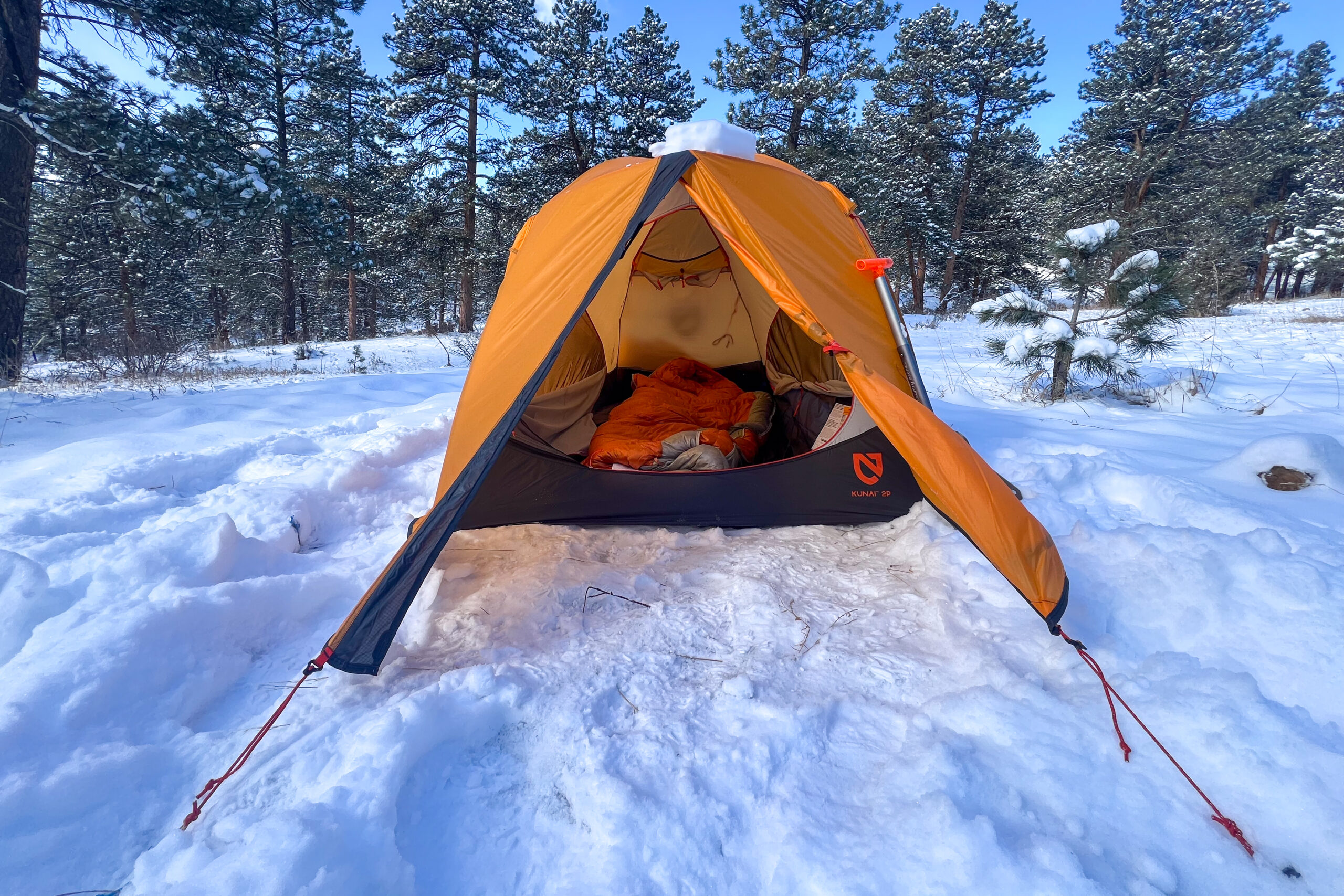 The Nemo Kunai 2 tent fully set up in a snowy forest under clear skies.