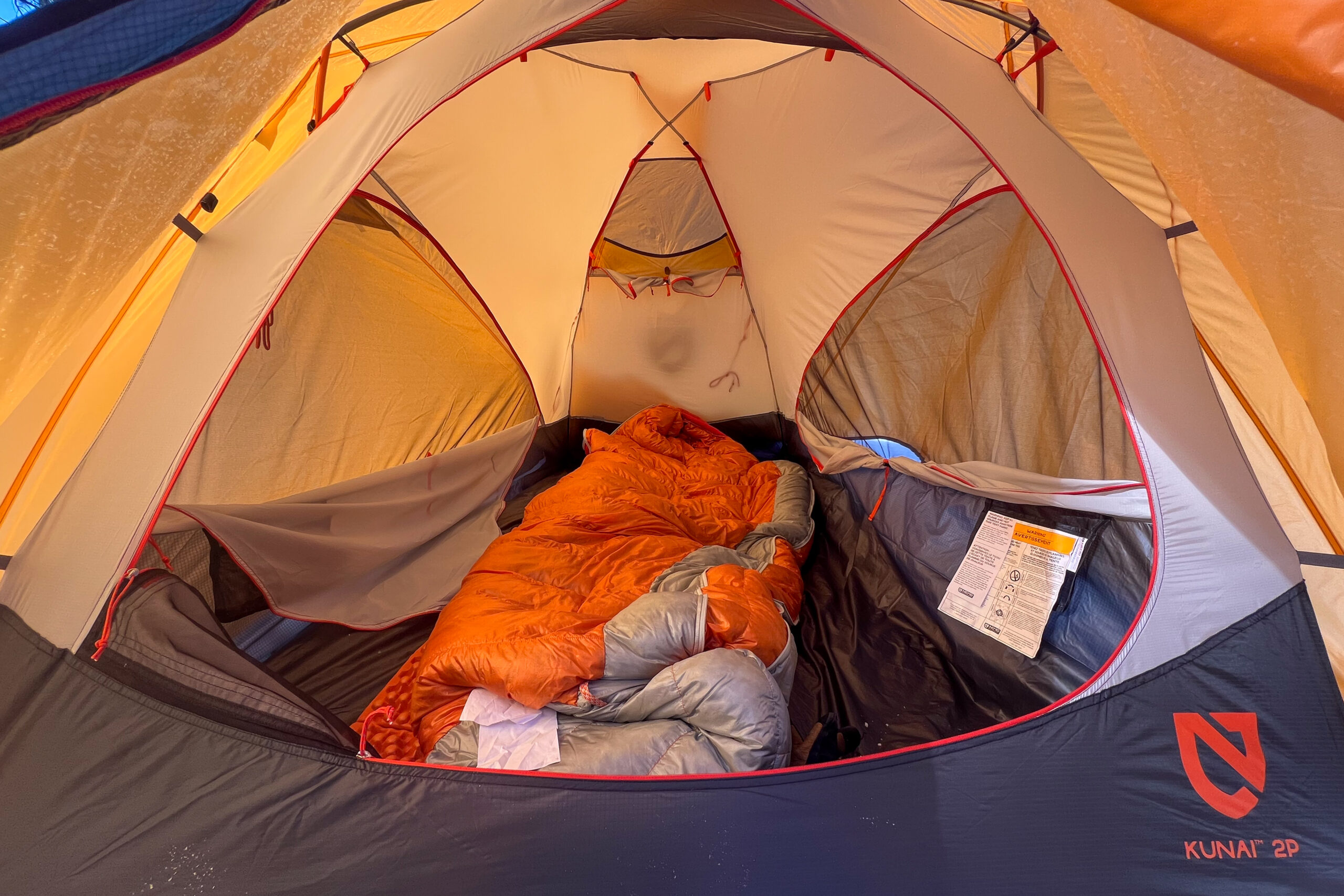 A close up of the interior of the Nemo Kunai tent, with an orange sleeping bag in the center.