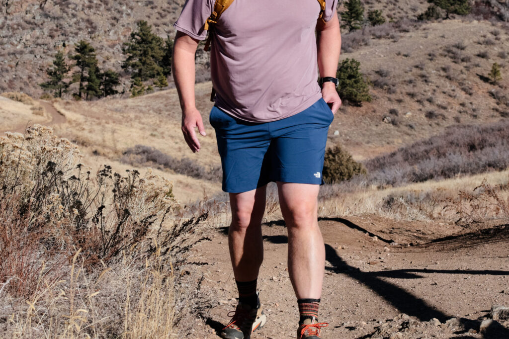 A man walks up a trail in blue shorts.