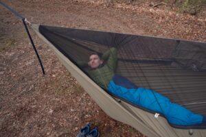 a man reclines in a green hammock