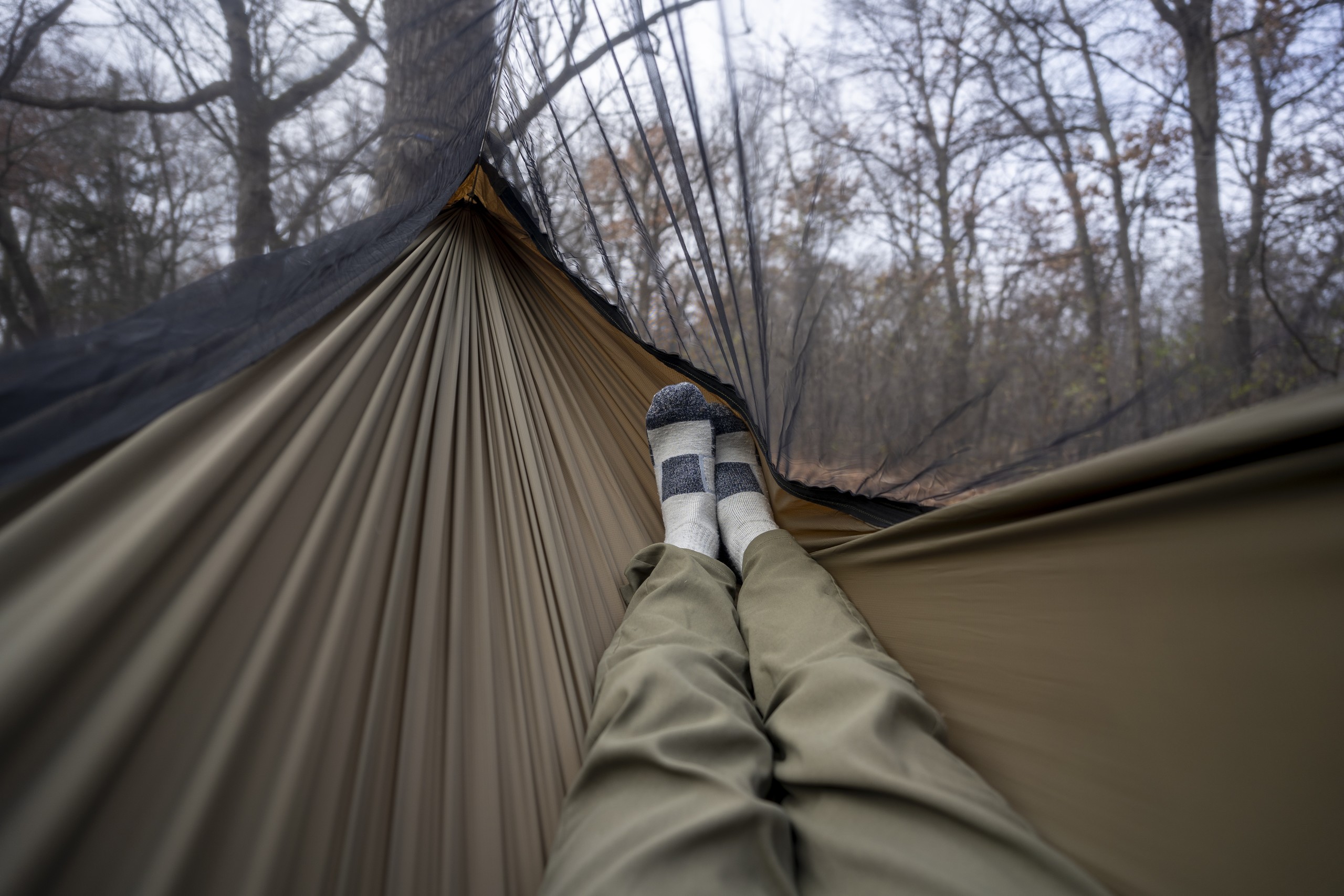 a pair of legs extend into a hammock interior from a point of view perspective