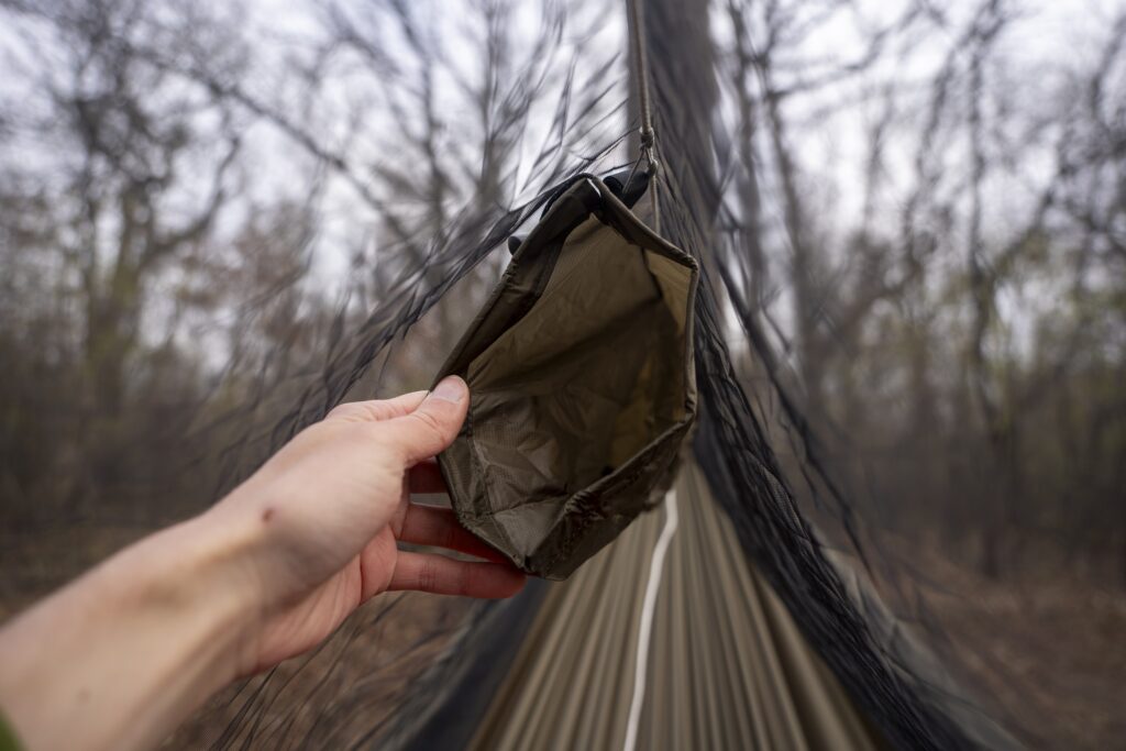 a hand holds open a ridgeline pocket on a hammock