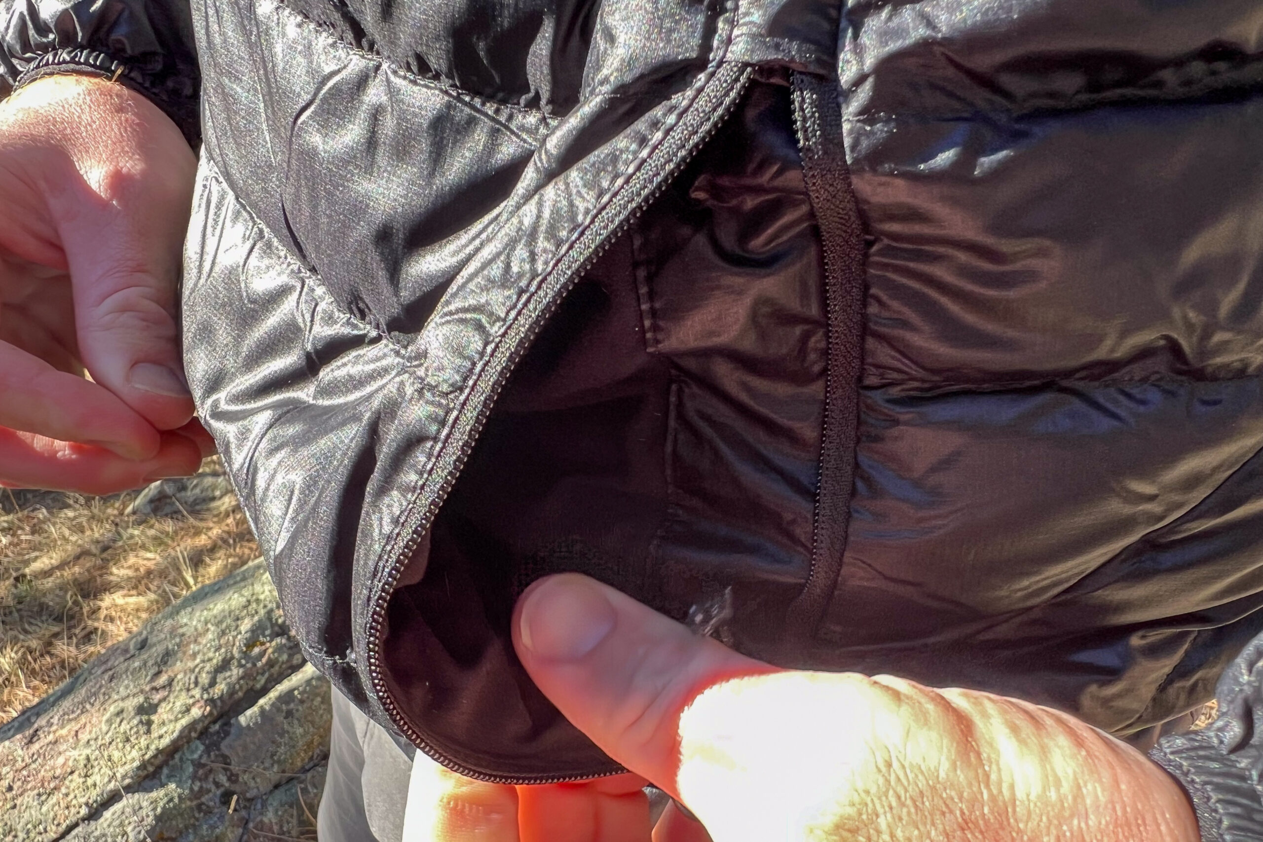 Close-up of the Outdoor Research Helium Down Hoody’s external fleece-lined zippered pocket, highlighting its cozy and functional design for warmth and secure storage.