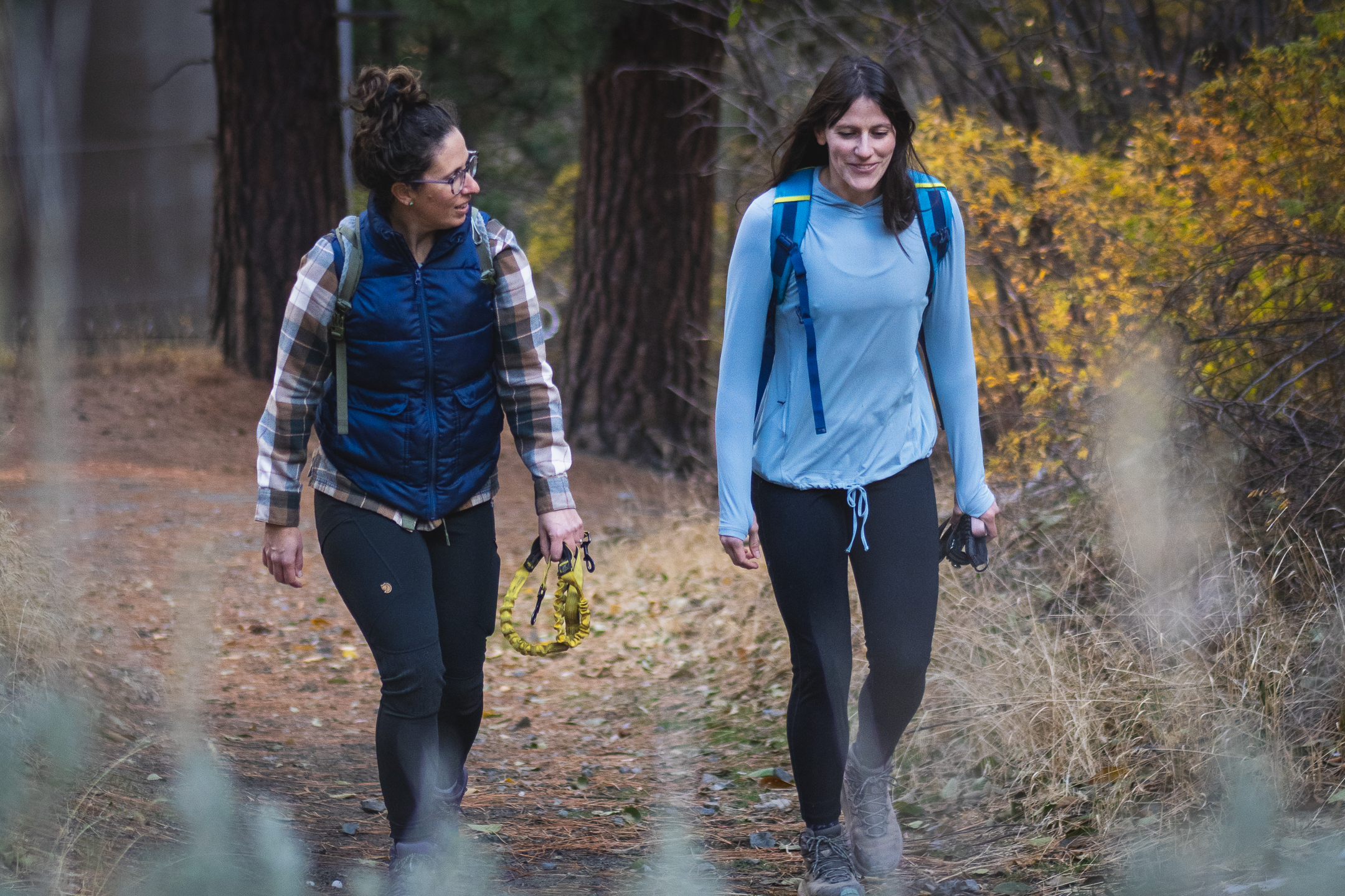 two women walking through forest in fall