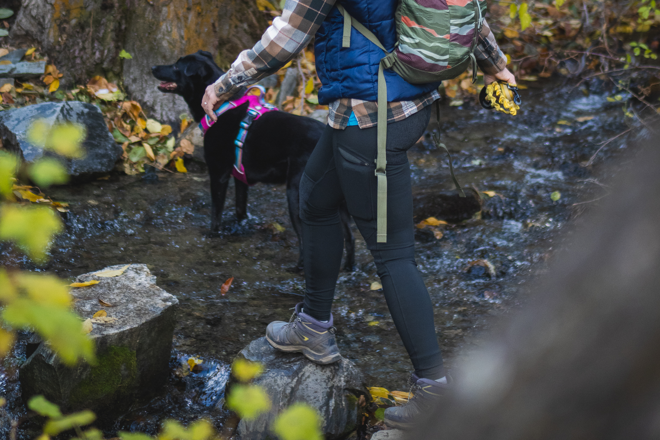 Woman hiking in black leggings, a bright blue shirt and a brown flannel, wearing a small backpack.