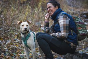 Woman hiking in black leggings, a bright blue shirt and a brown flannel, wearing a small backpack.