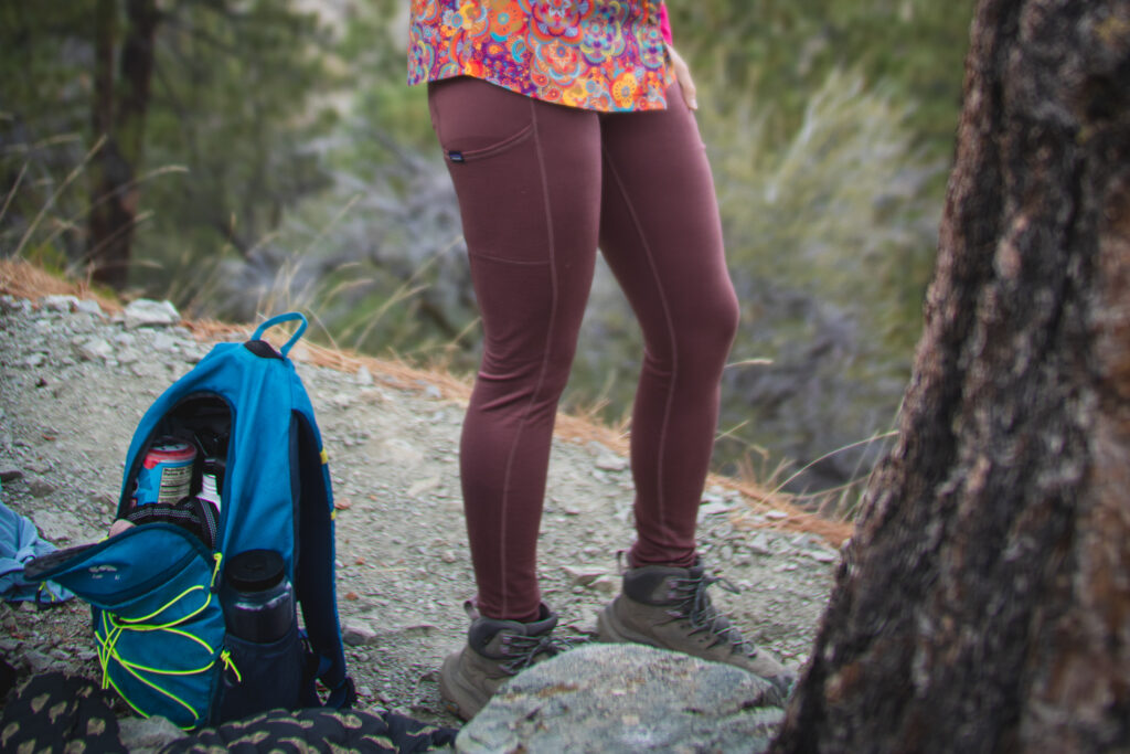 bottom half of person in pastel pink leggings, with a blue backpack on the ground next to their feet