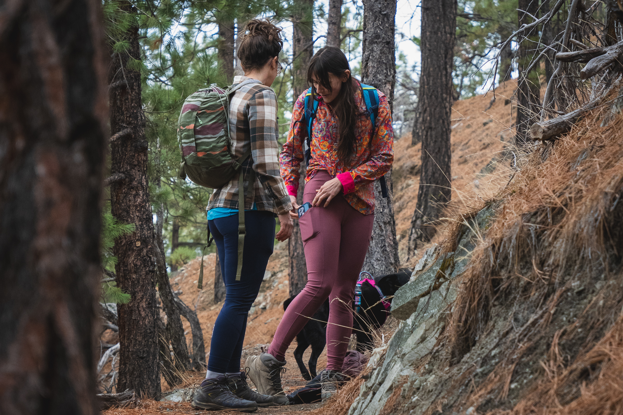 two people stopped on a trail, talking, one in blue leggings, and one in pastel pink leggings